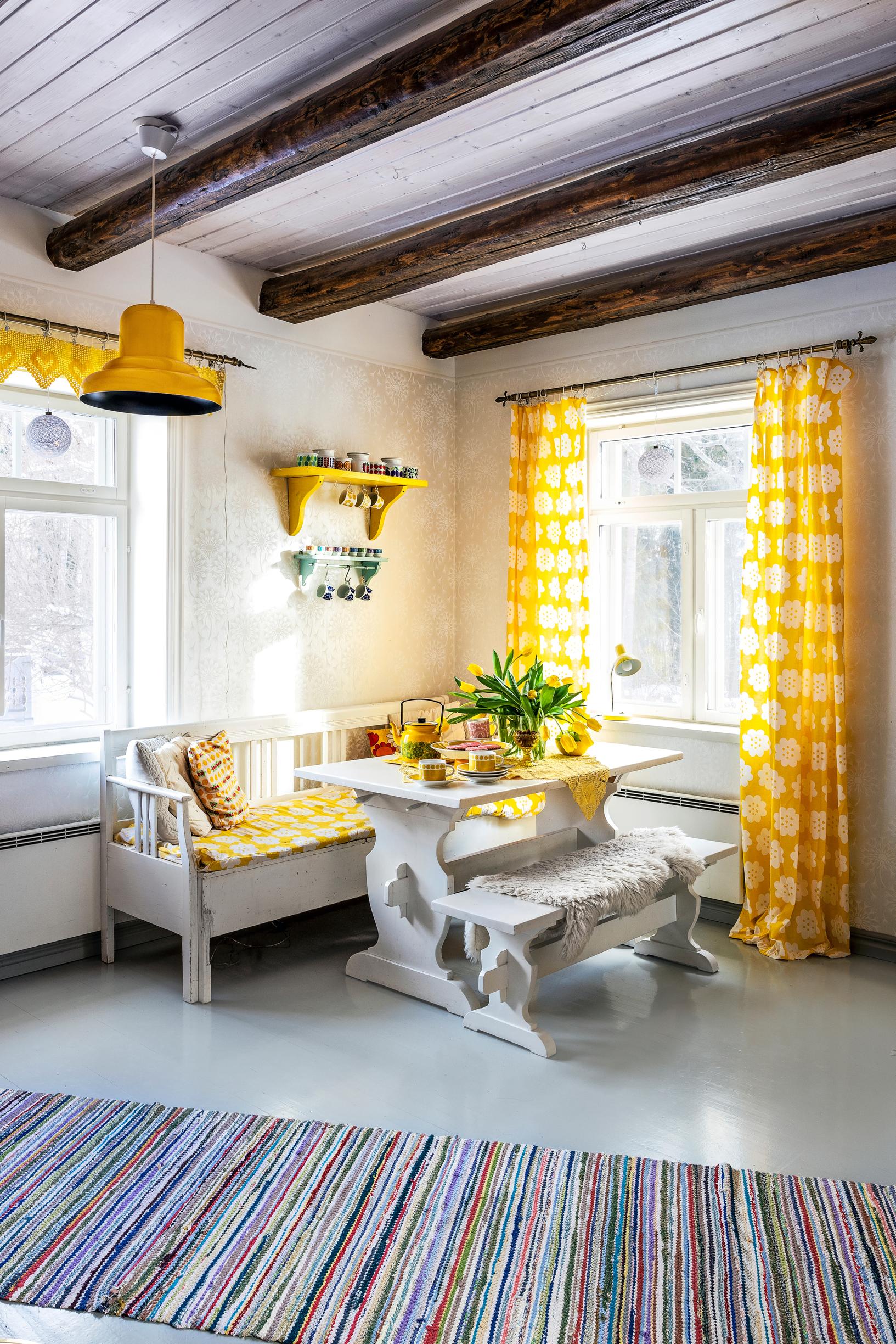 Keltainen keittiö pirttikalusteineen.