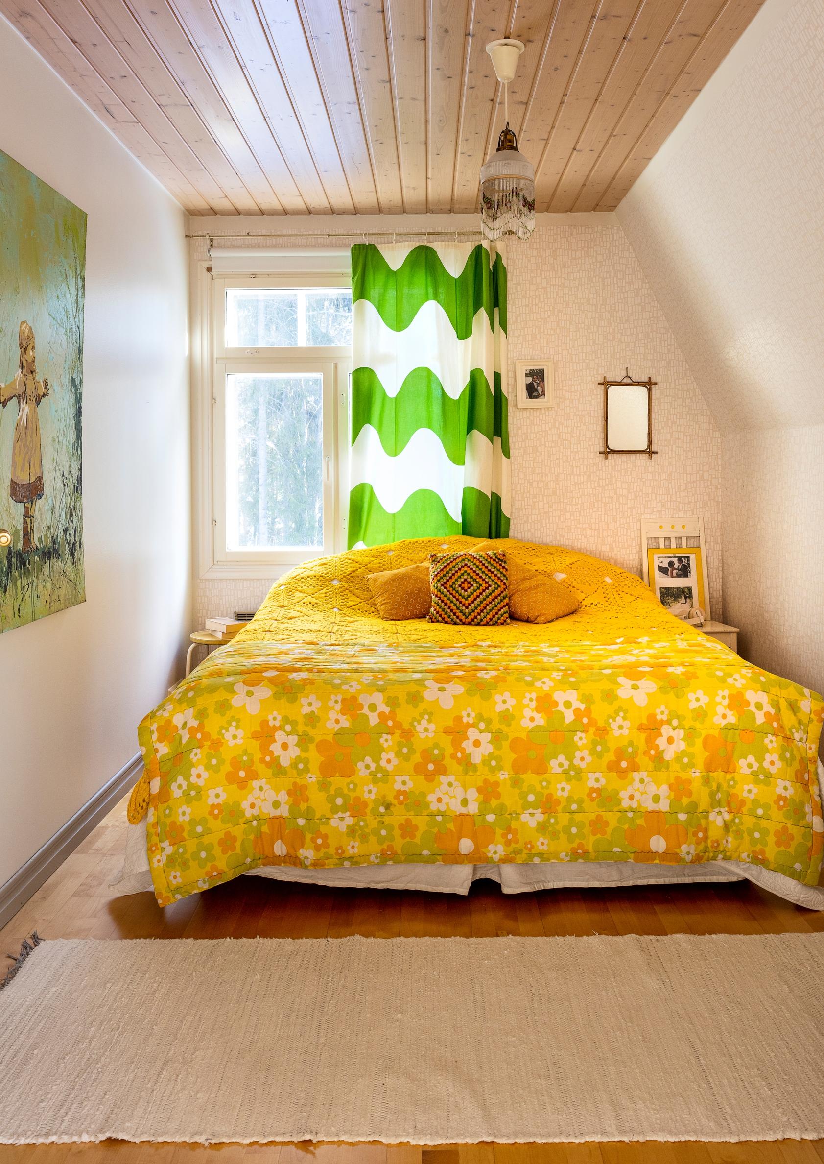 Samulin ja Elisan makuuhuone keltaisine vintagetäkkeineen ja Lokki-verhoineen.