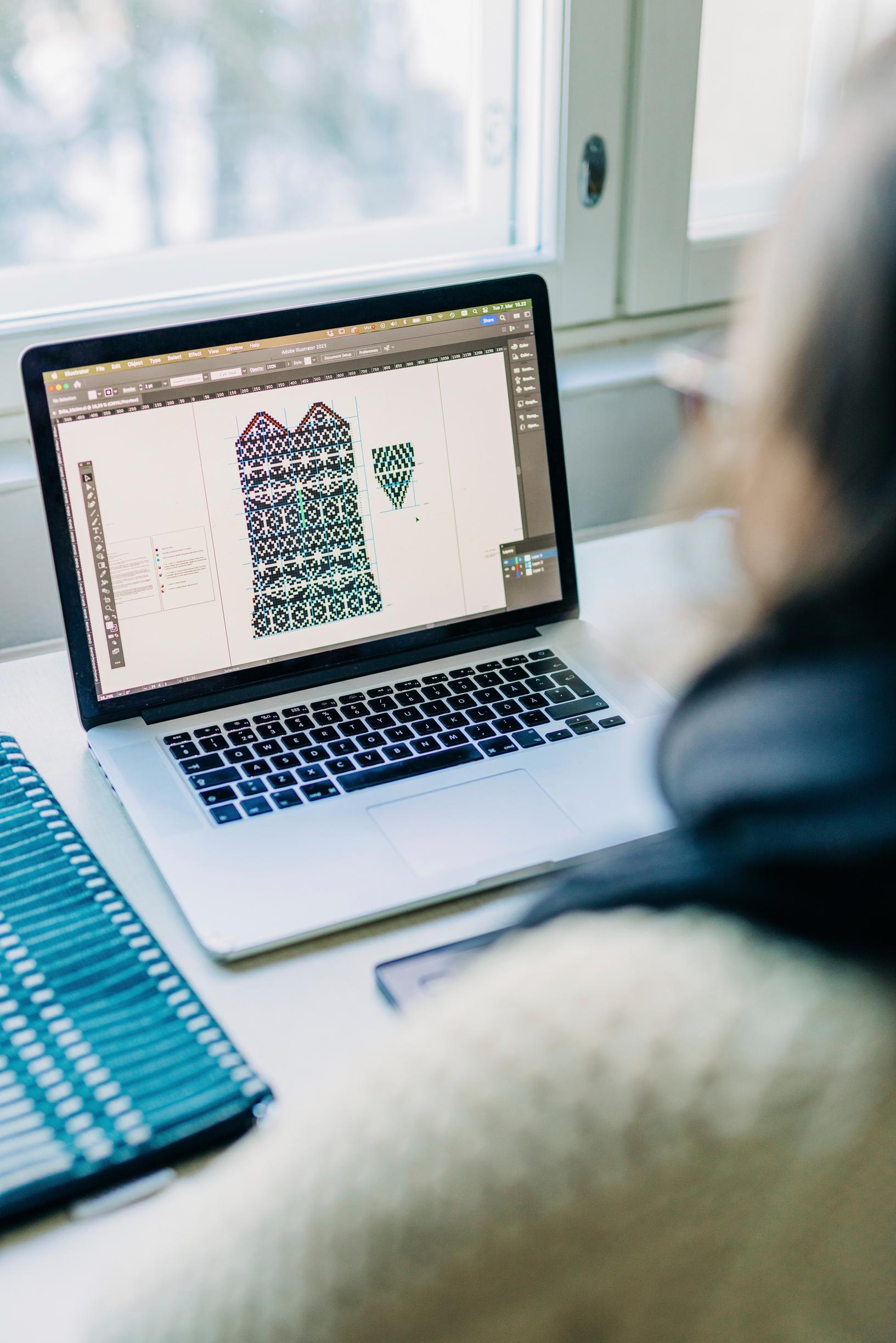 Minttu Wikberg tietokoneen ääressä suunnittelemassa neulekuviota.