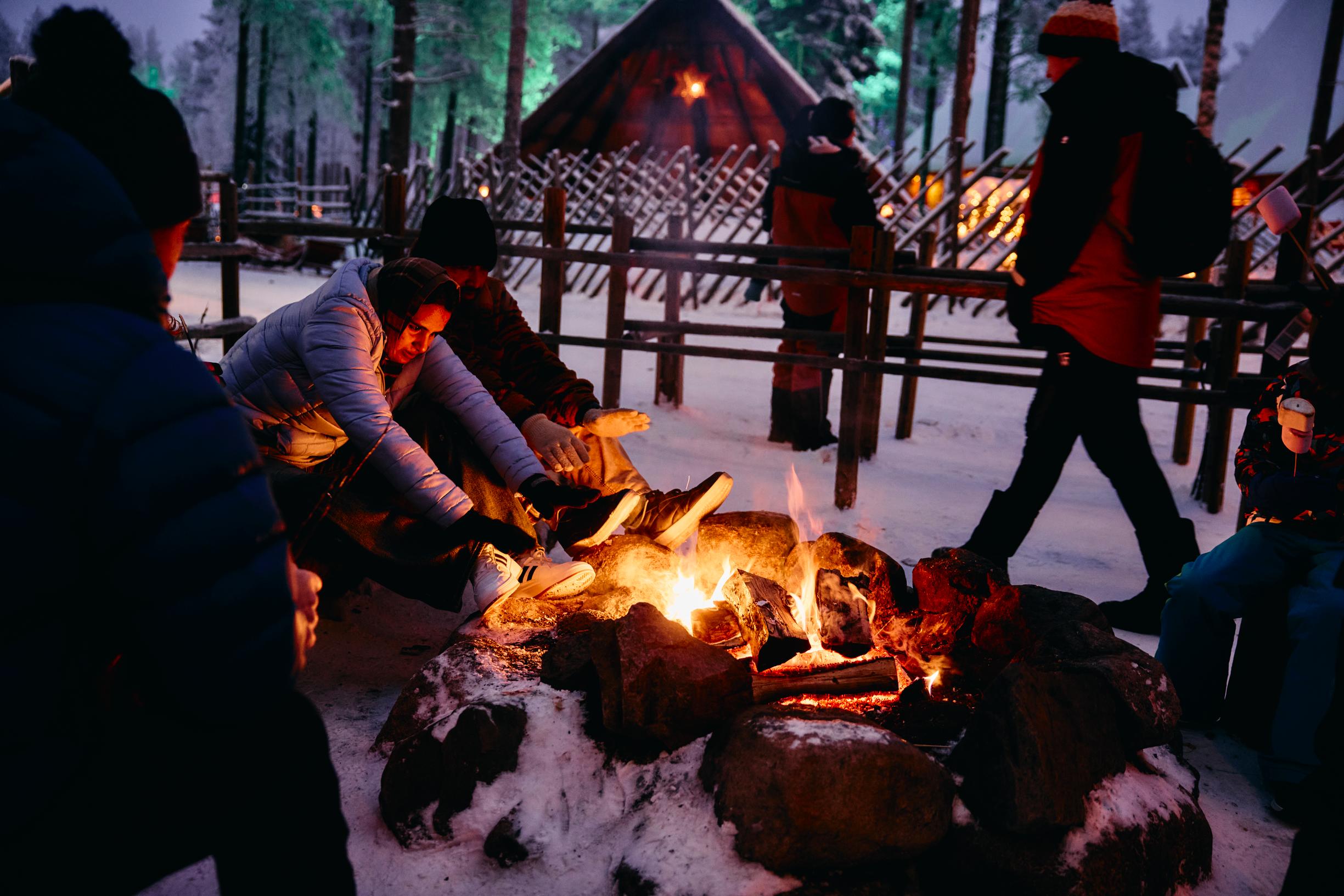 Joulupukin Pajakylä: turisteja lämmittelemässä nuotiolla