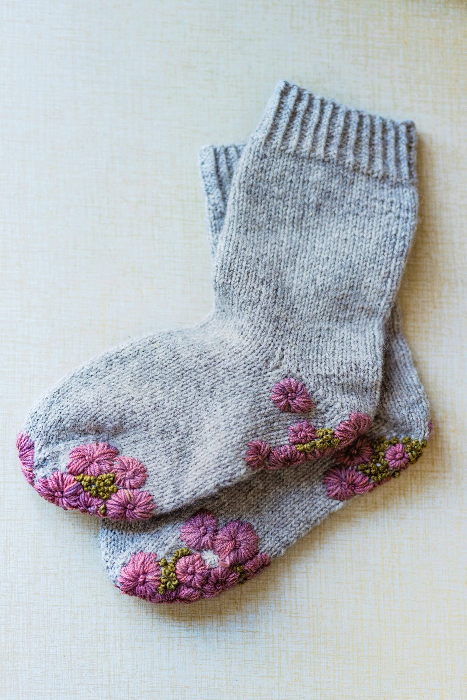 Villasukat, joiden kantapäähän ja pohjaan on parsittu vaaleanpunaisia kukkia.