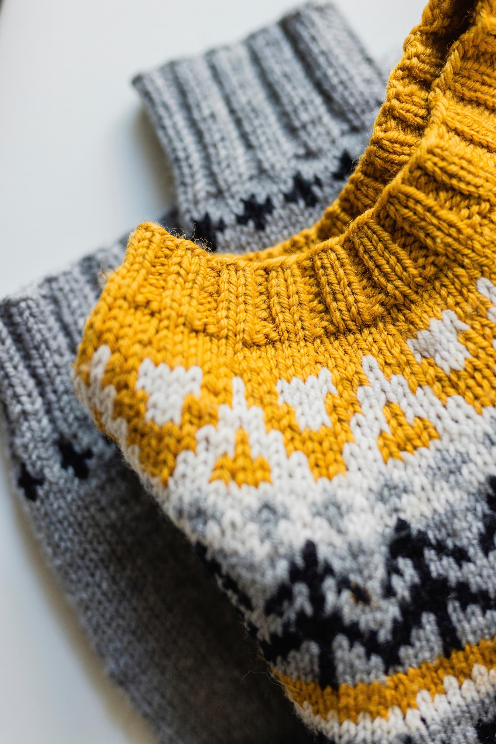 Kaarrokeneule, joissa väreinä keltainen, harmaa, musta ja valkoinen.