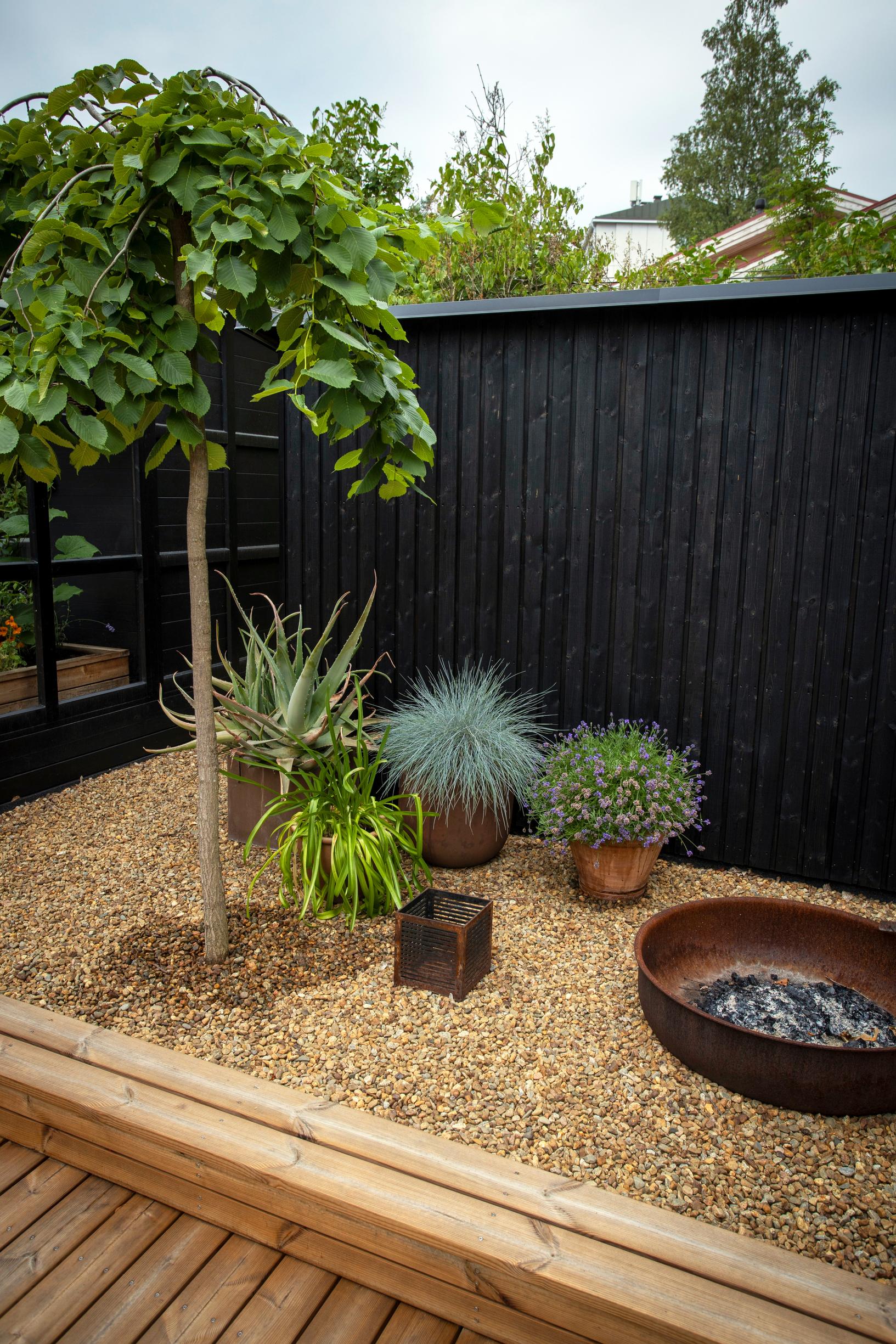 Sateenvarjojalava, ruukkuistutuksia ja pieni tulipaikka soralla