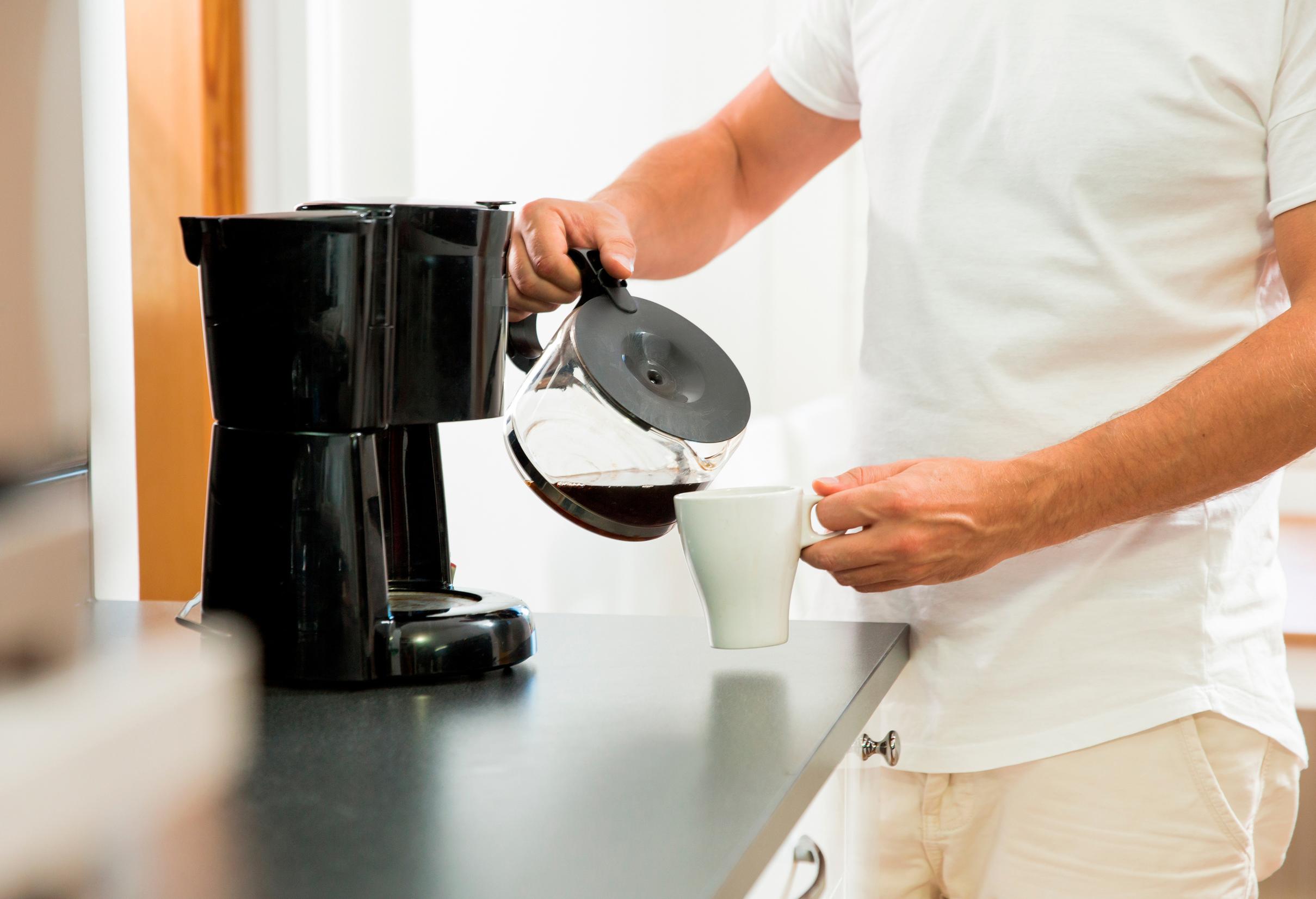 Mies kaataa kahvia mukiin