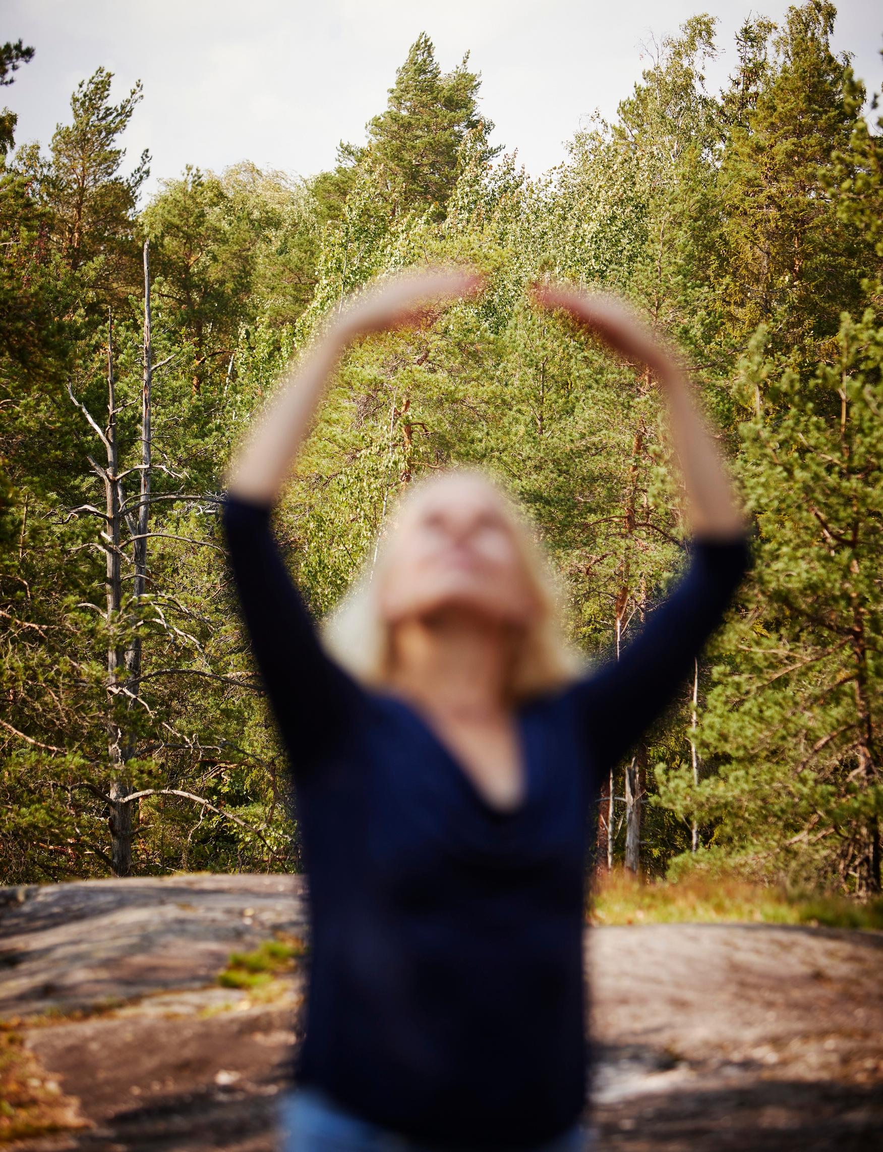 nainen nostaa kädet ylös balettitanssijan asentoon seistessään kalliolla