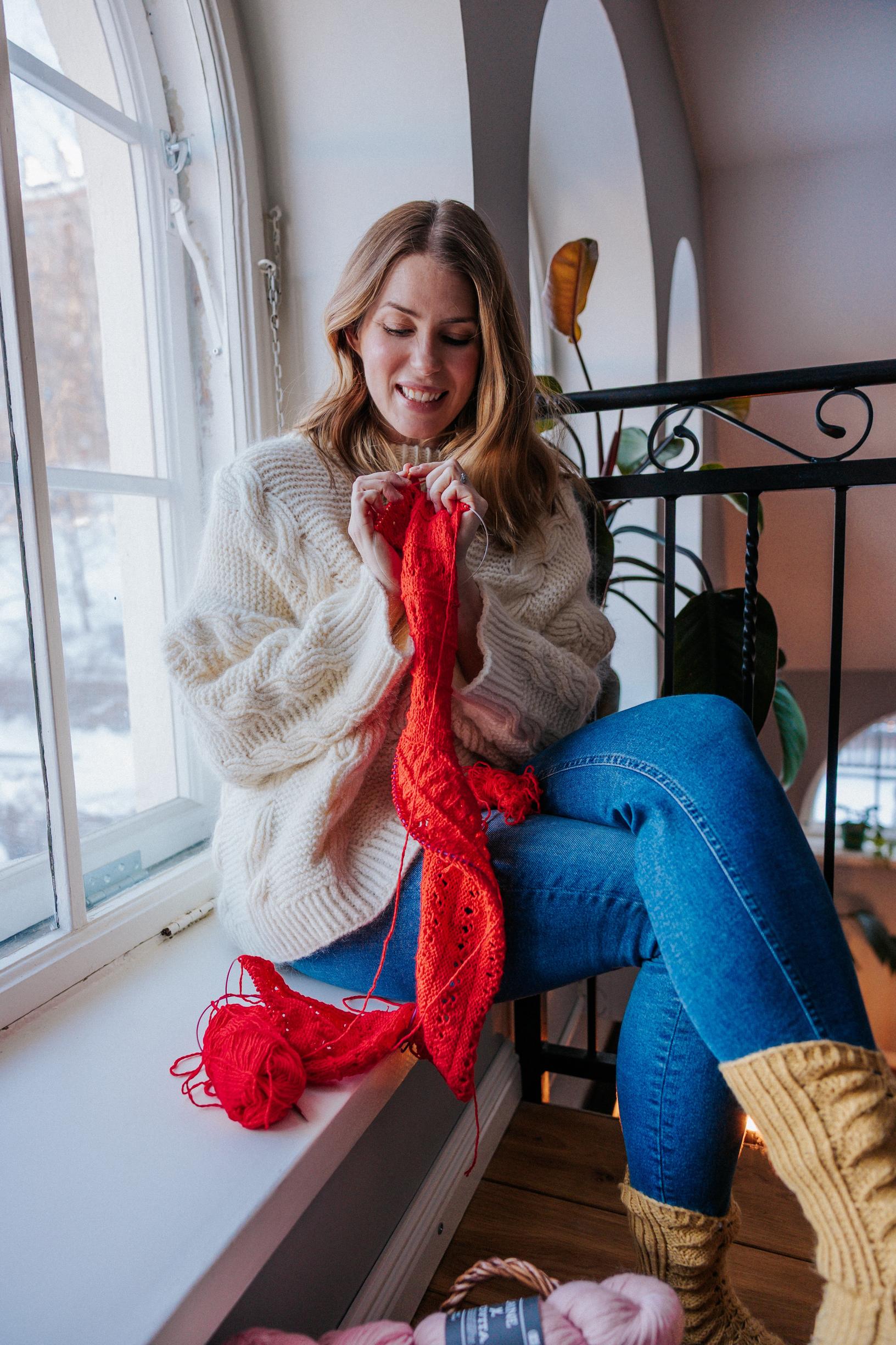 Marita Paasonen neuloo ikkunan ääressä