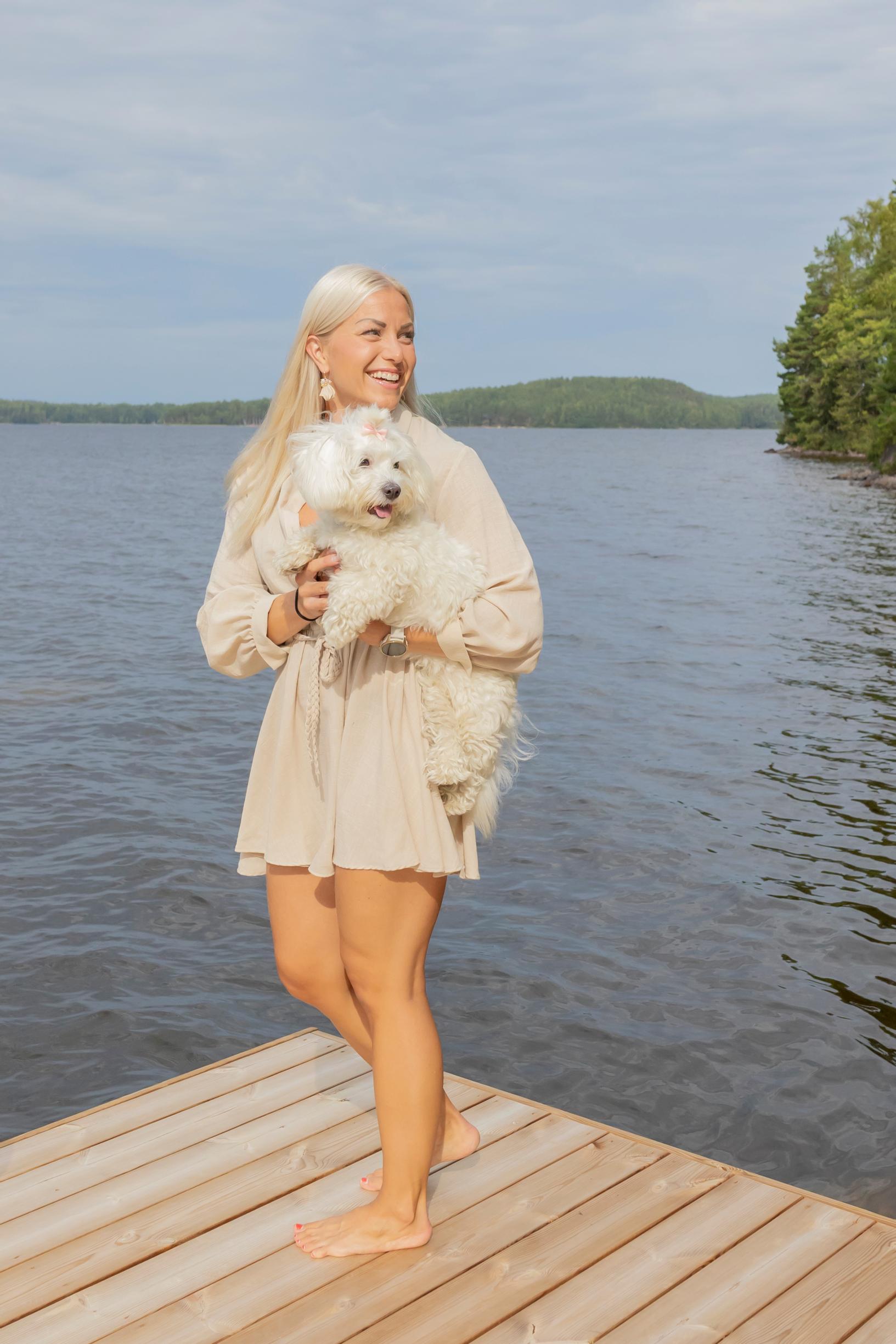 Pauliina Räisänen seisoo laiturilla Lilli-koira sylissään