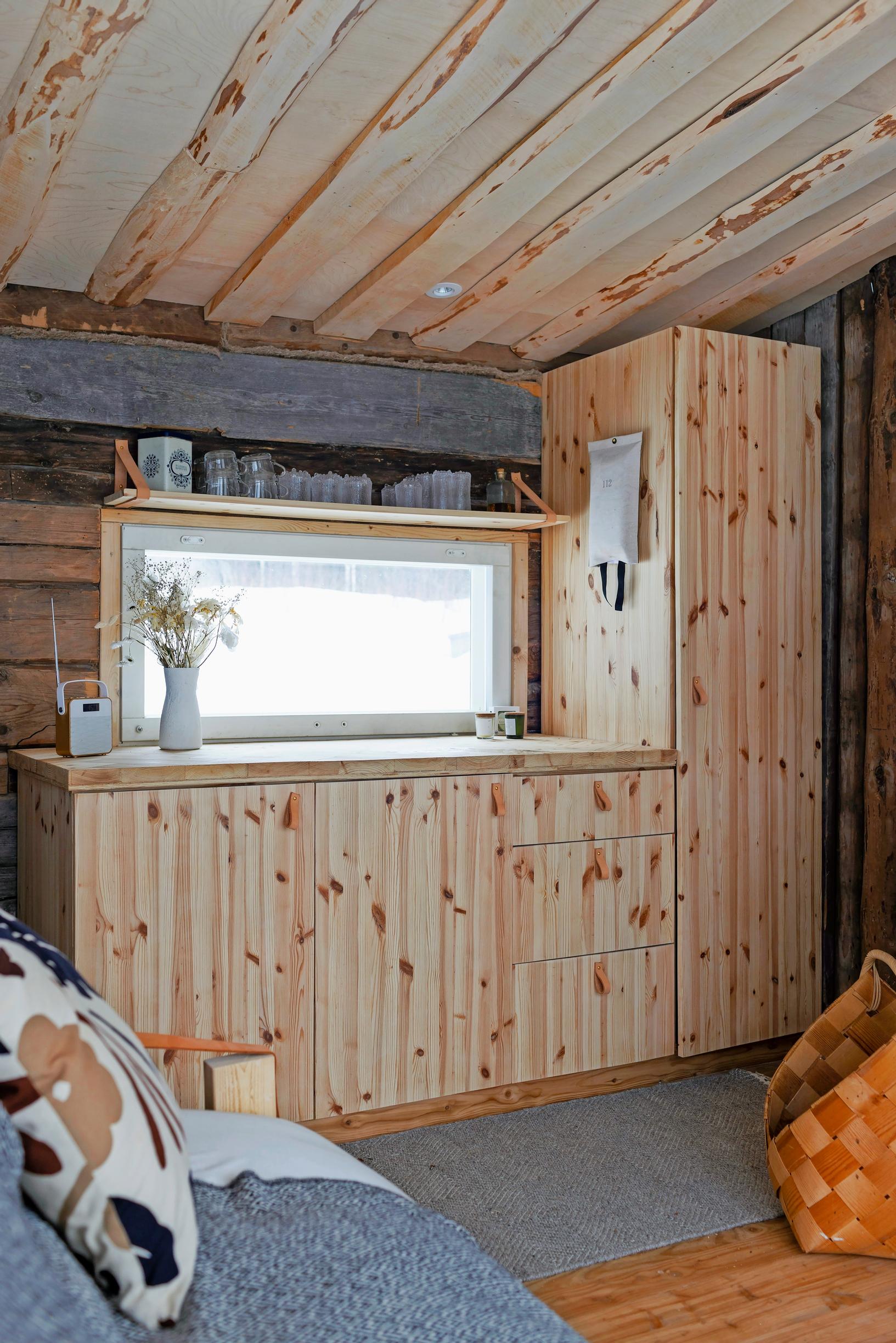 mäntykaapisto ikkunan edessä, sohva ja pärekori