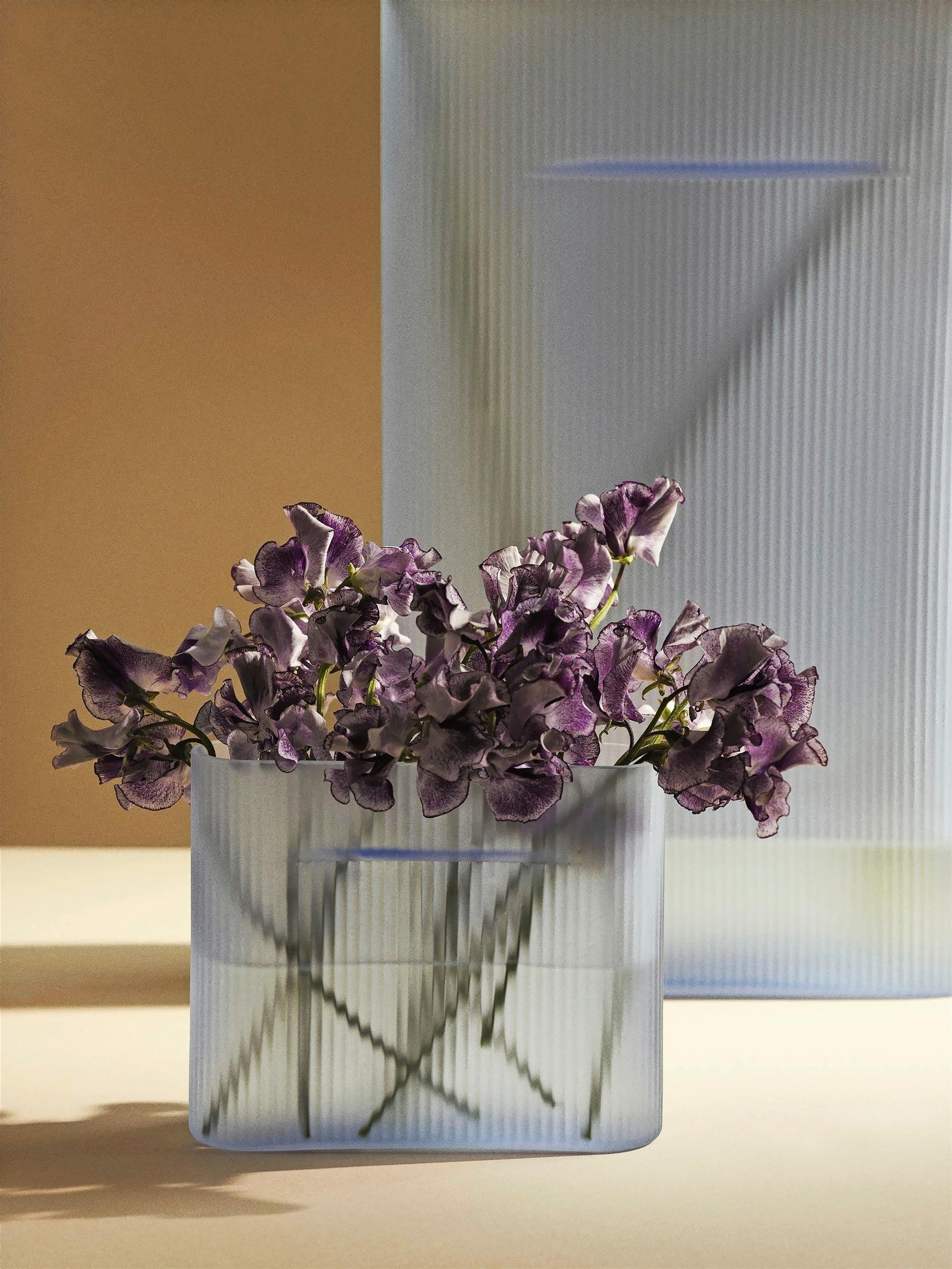 Muuton Ridge-maljakko huurrelasisena versiona, violetteja kukkia 