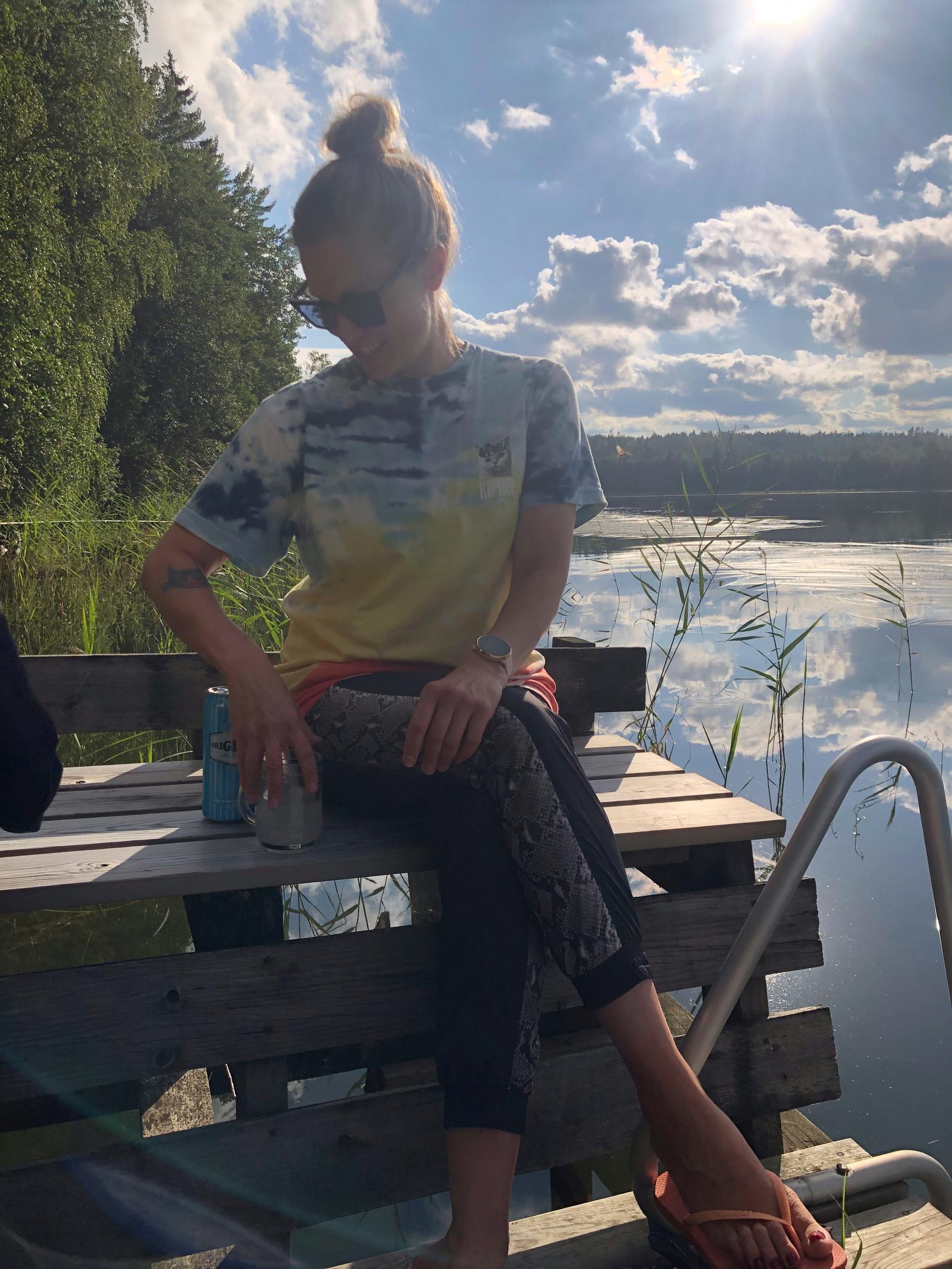 Meri-Tuuli Väntsi istuu laiturin penkillä, aurinko paistaa ja valkoisia pilviä taivaalla
