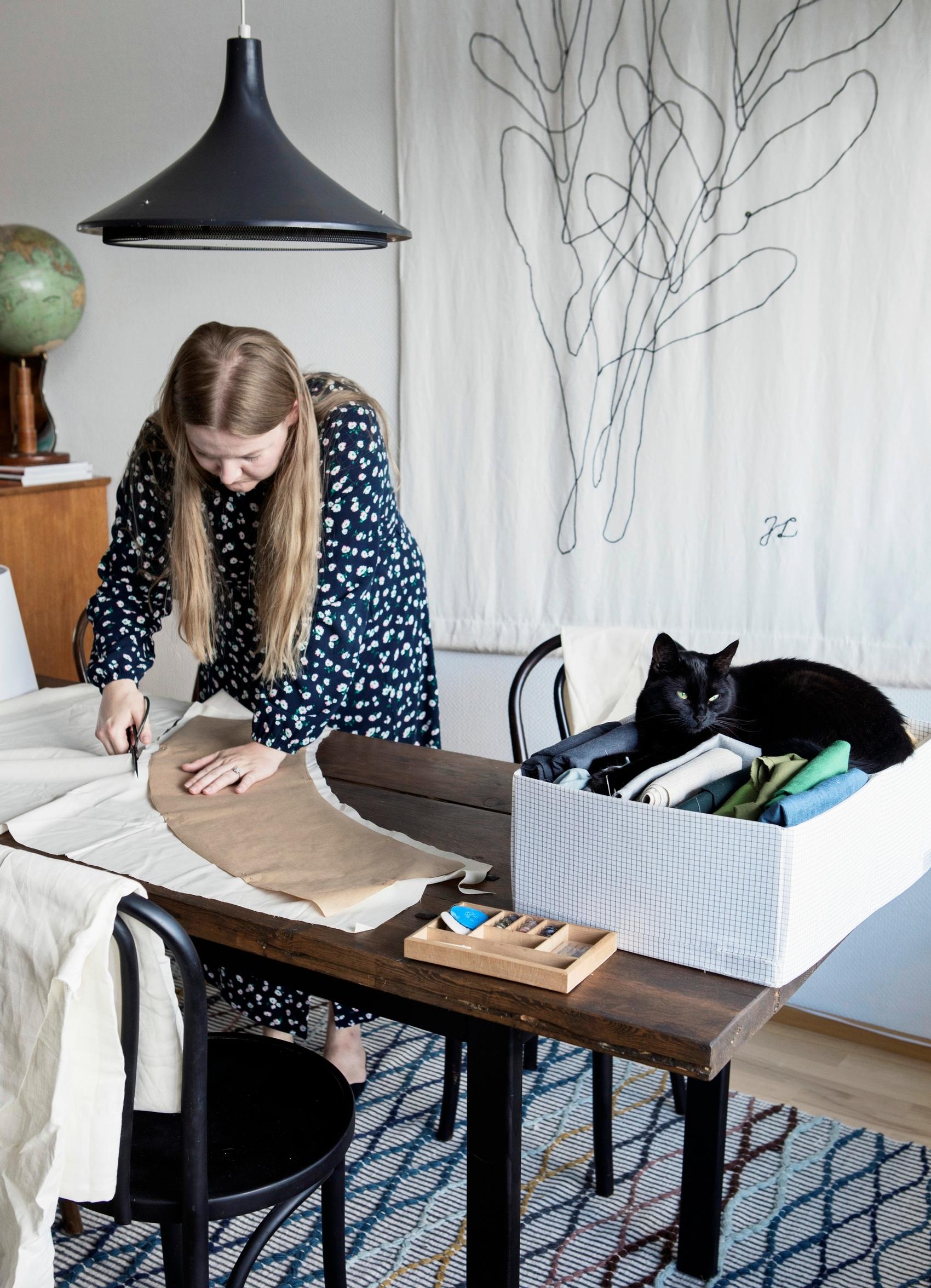 Julia Lillqvist ja Nova-kissa työpöydän ääressä