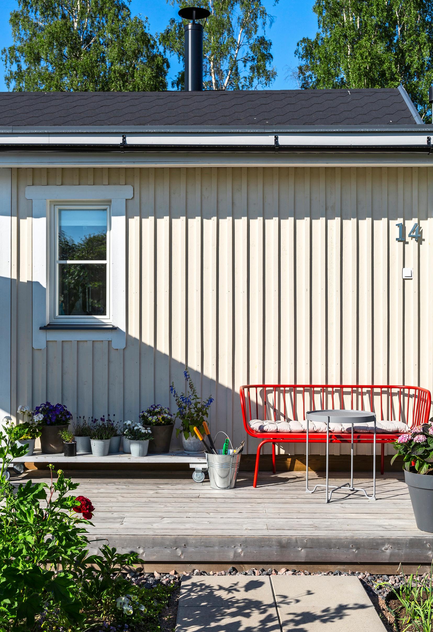 Punainen metallipenkki pikkuterassilla