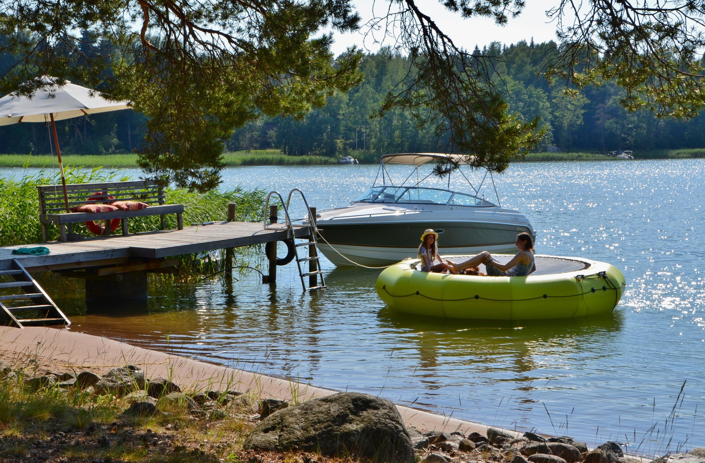 lapset vesitrampoliinilla laituri ja moottorivene 