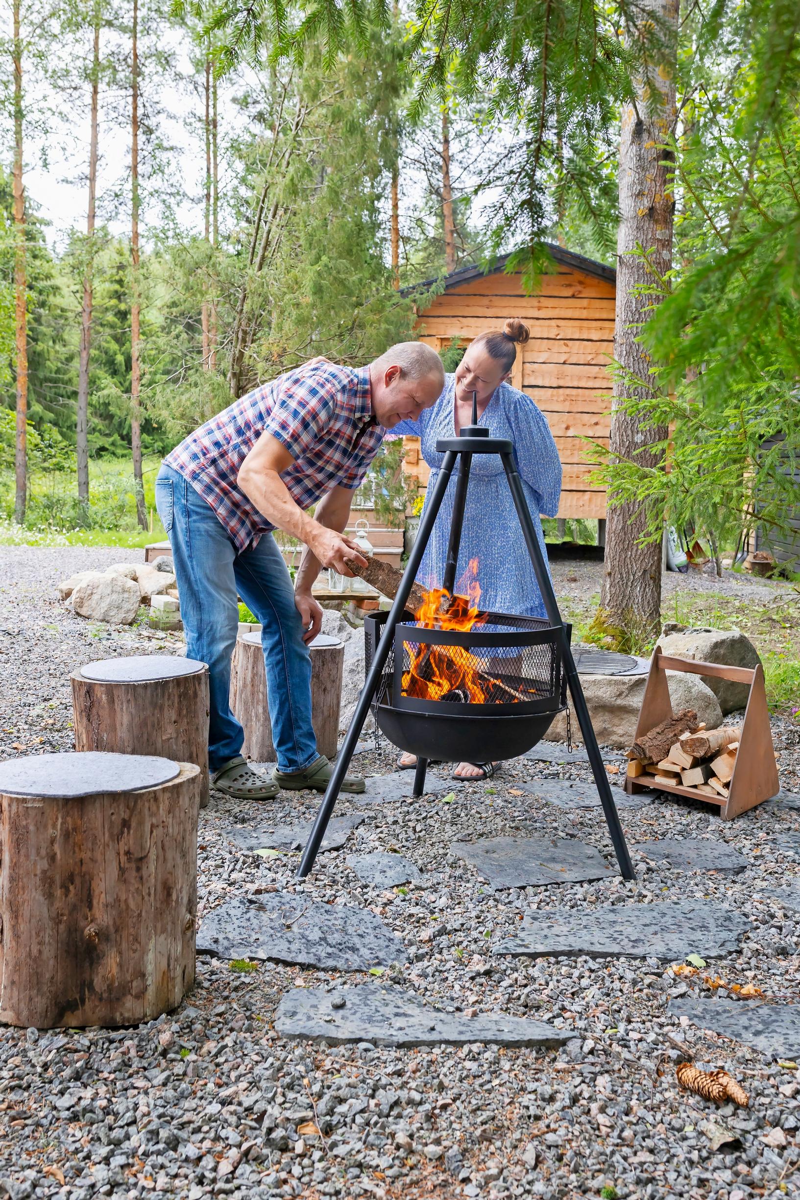 Jutta ja Pasi Taavitsainen tulisijan ääressä Sipoon saunamökkinsä pihalla