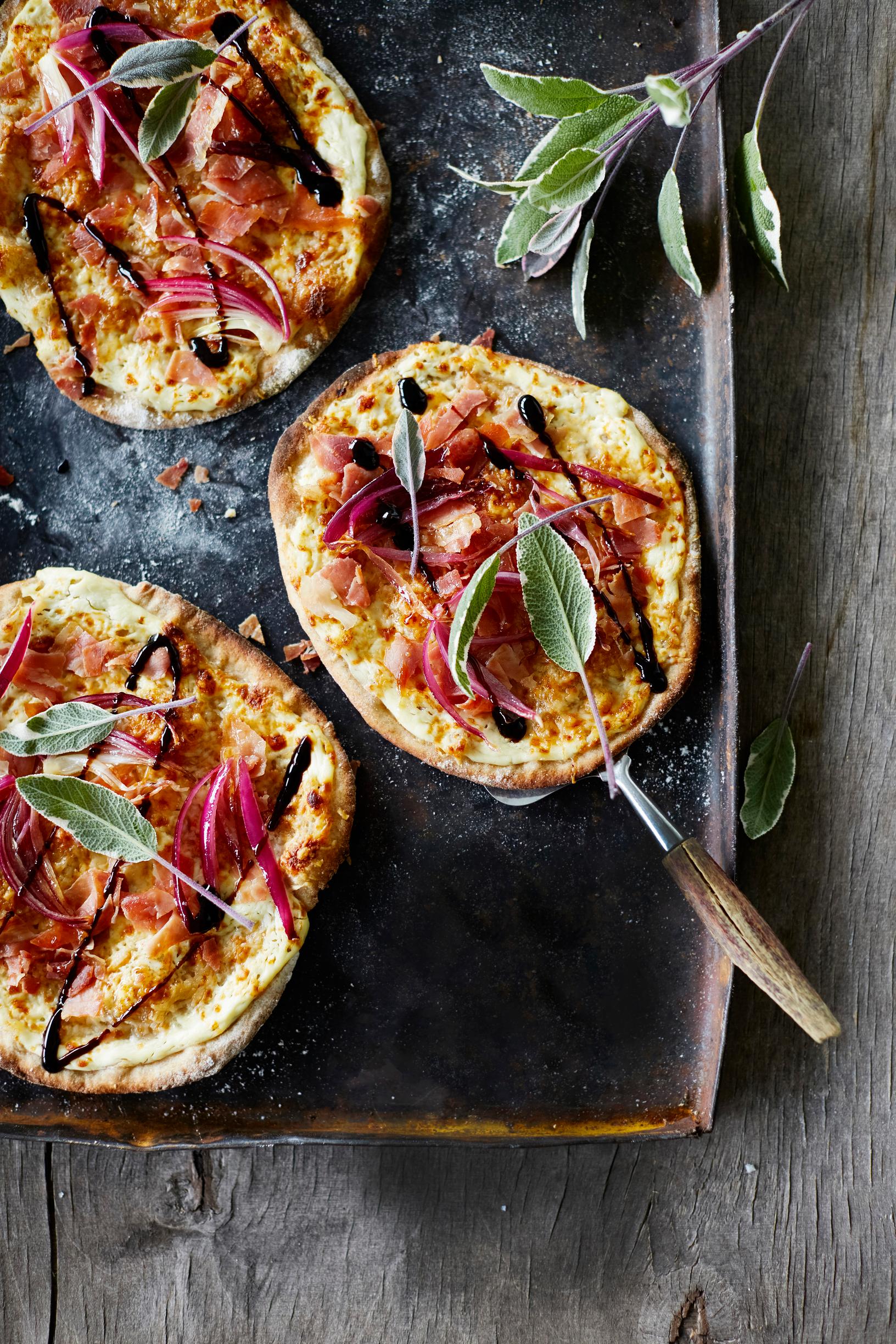 Pienet pizzat, joiden päällä punasipulia ja balsamicoa.
