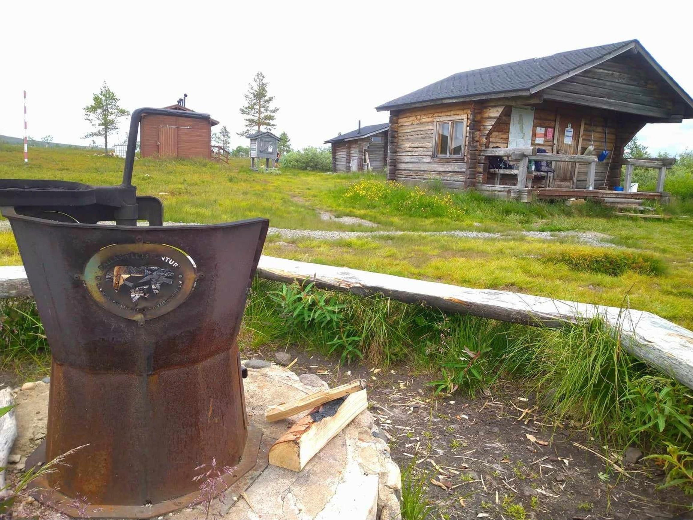 taustalla varaustupa, edessä nuotiopaikka