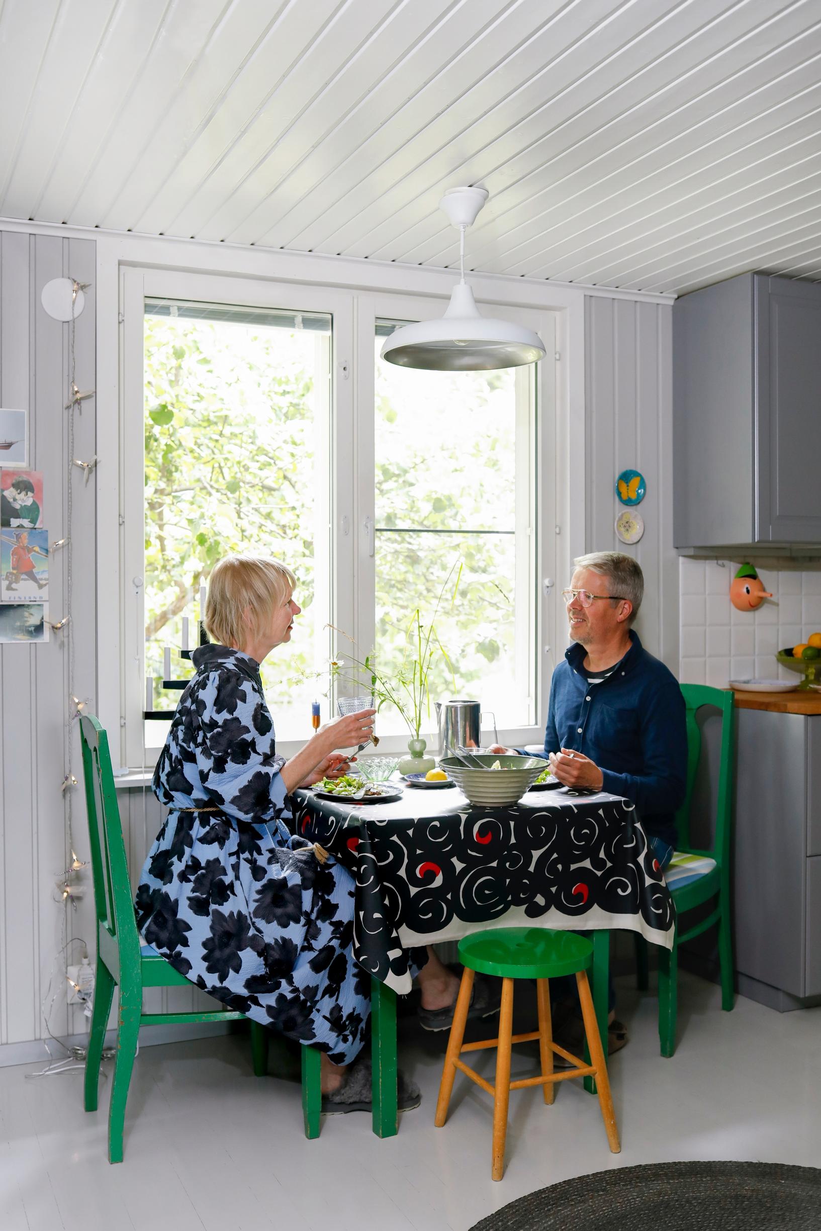 Pariskunta istuu vihreässä pöytäryhmässä ikkunan edessä.