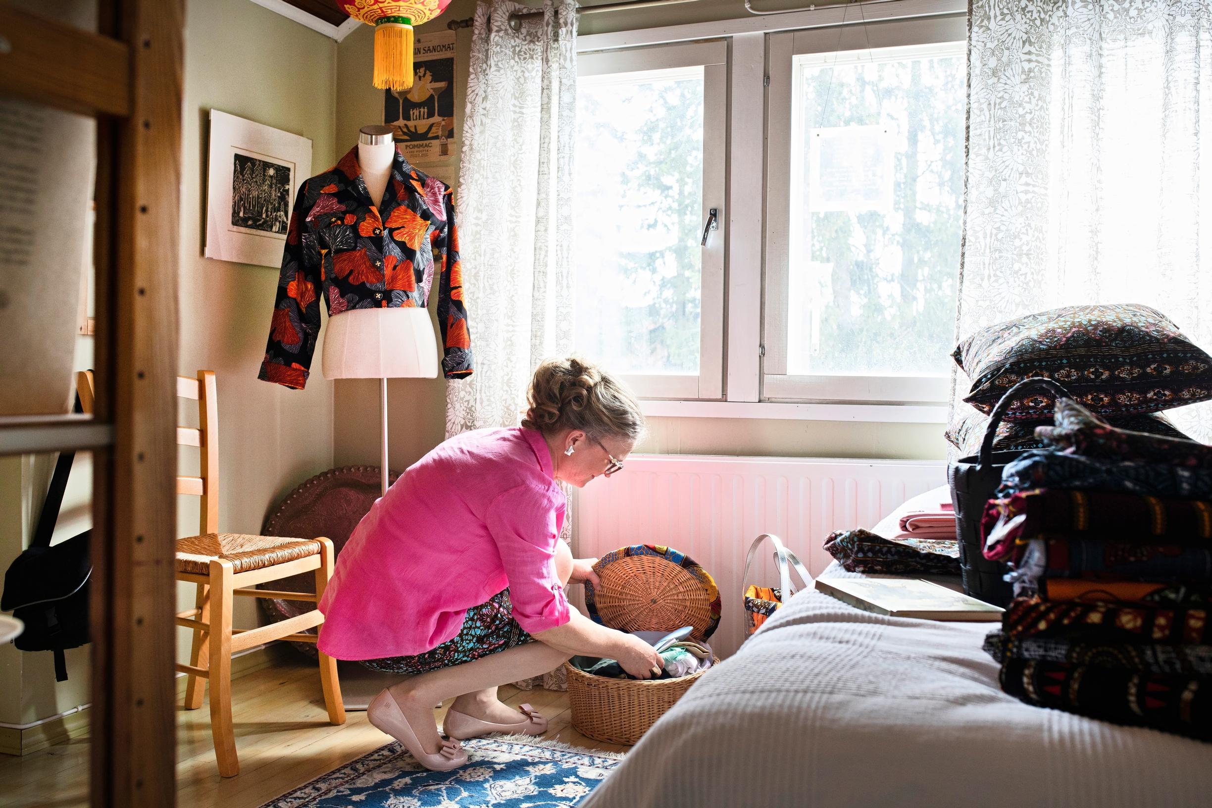 nainen kumartuneena kohti koria omassa huoneessaan