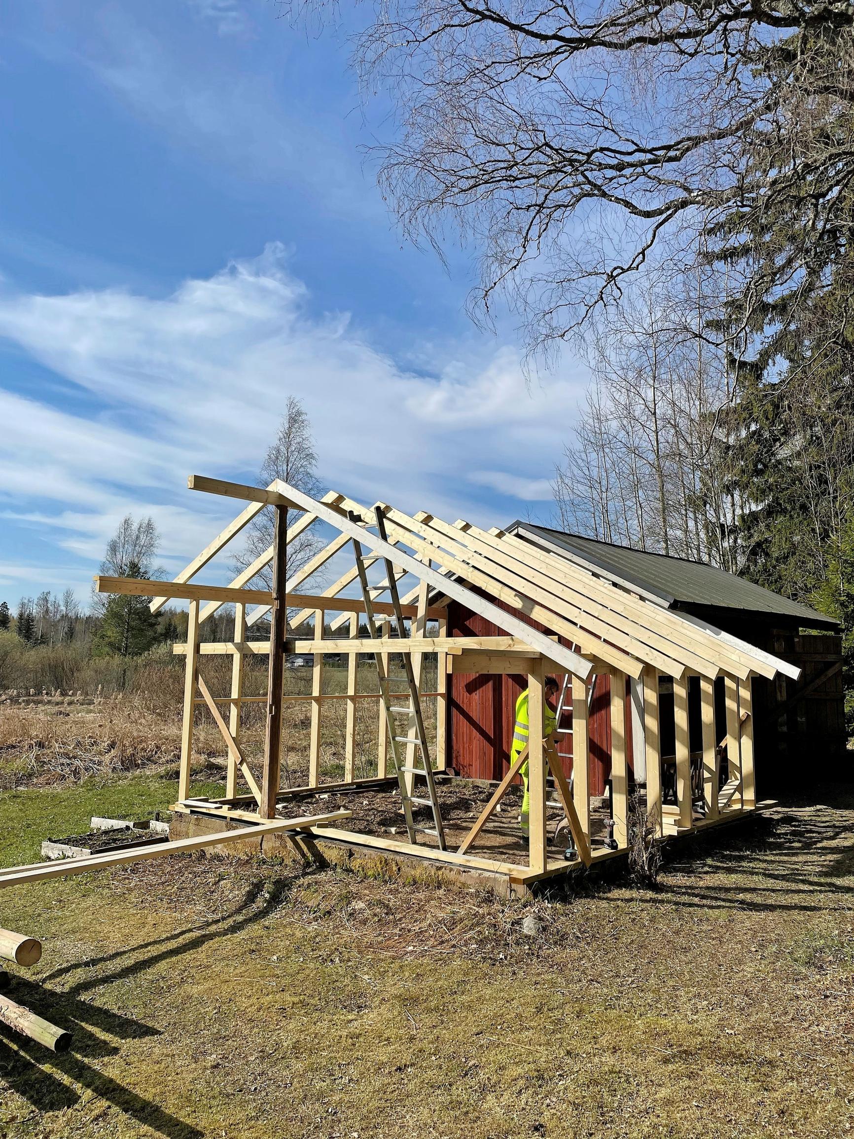 puurakennuksen kehikko vanhan rakennuksen vieressä