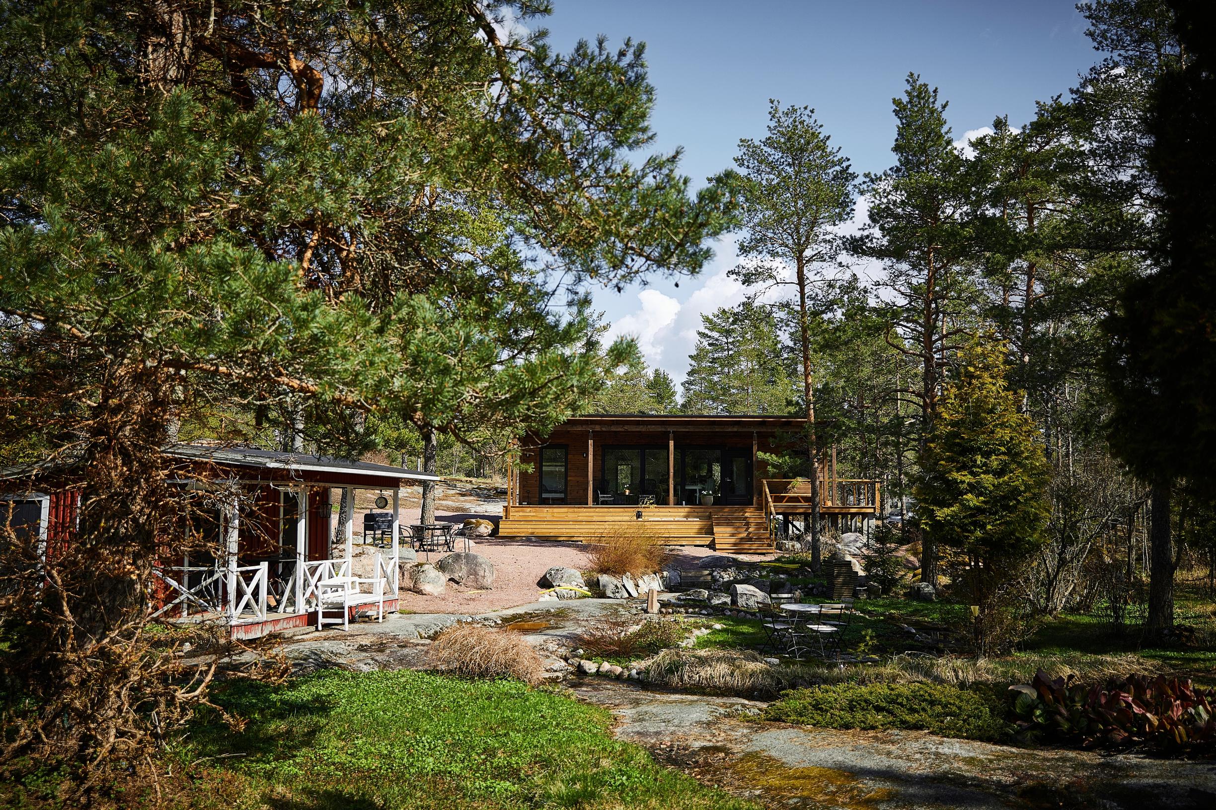 punainen varasto ja uusi hirsimökki kallioiden ja mäntyjen keskellä