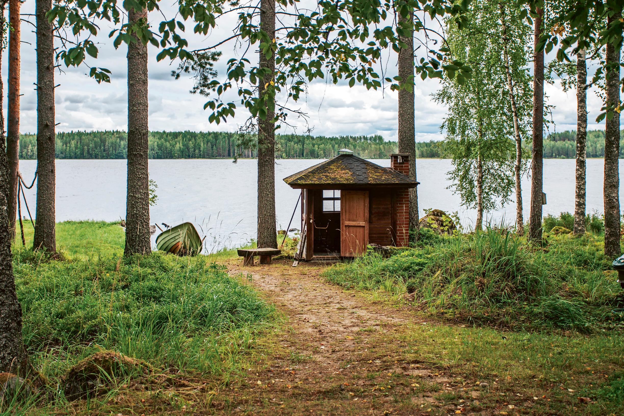 Kulahtanut rantavaja ja järvinäkymä puiden lomassa.