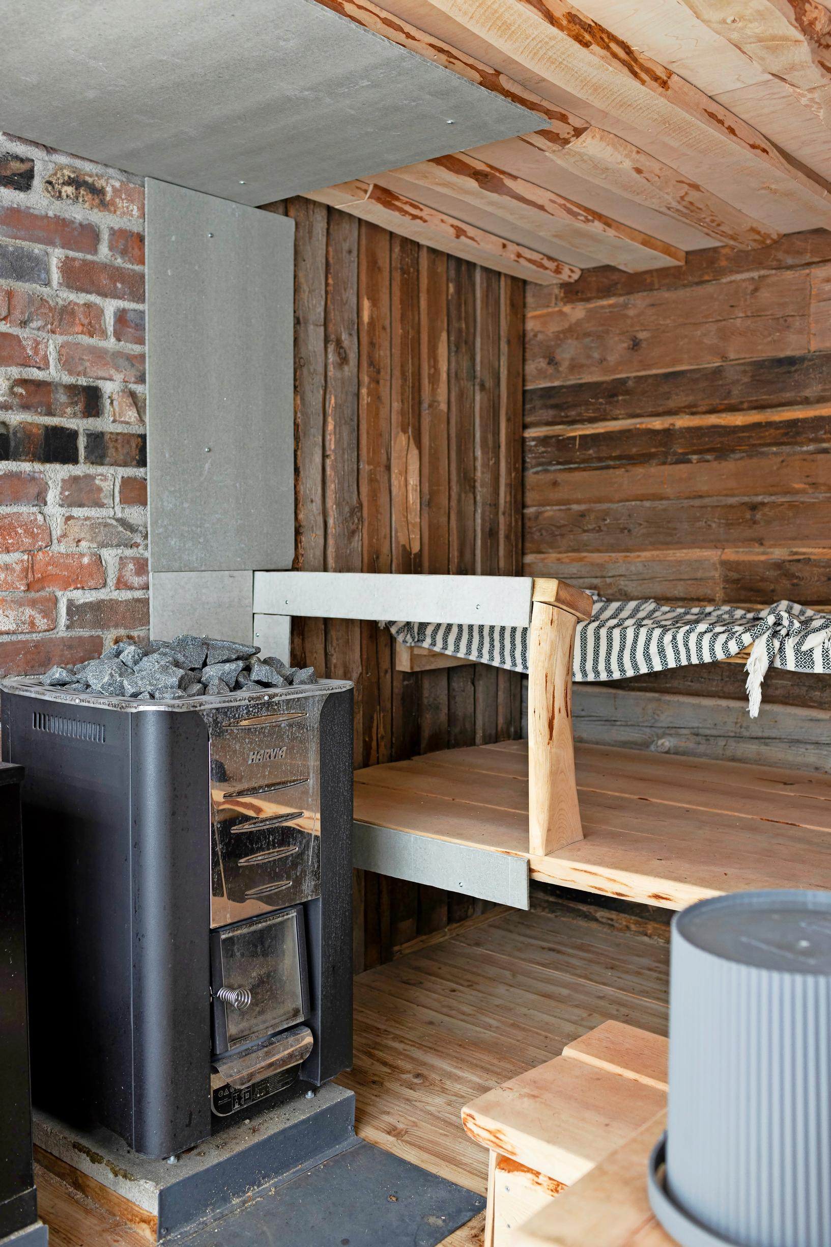 puu- ja tiiliseinäinen sauna, lauteilla raidallinen liina, kiuas