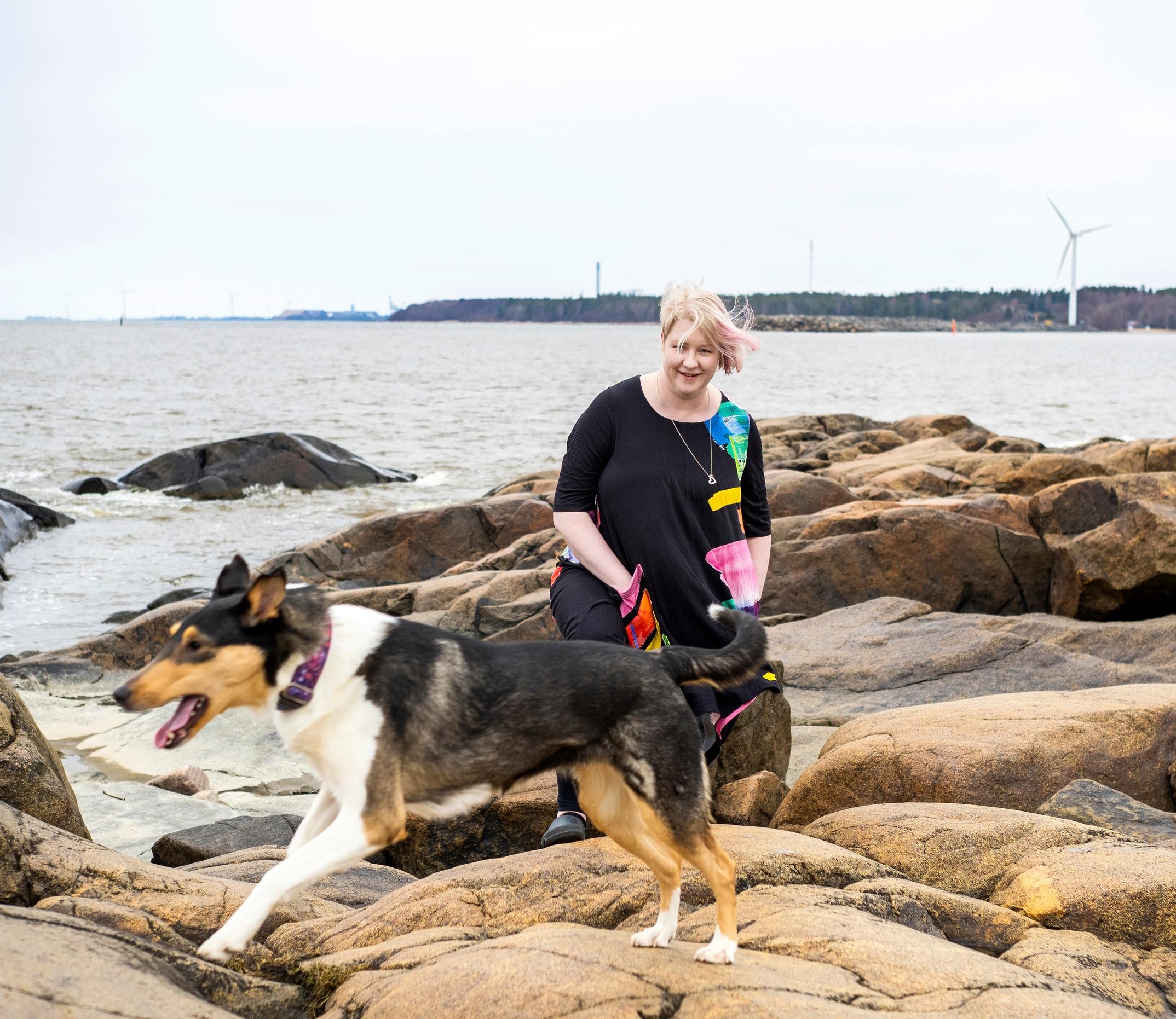 nainen ja koira rantakalliolla