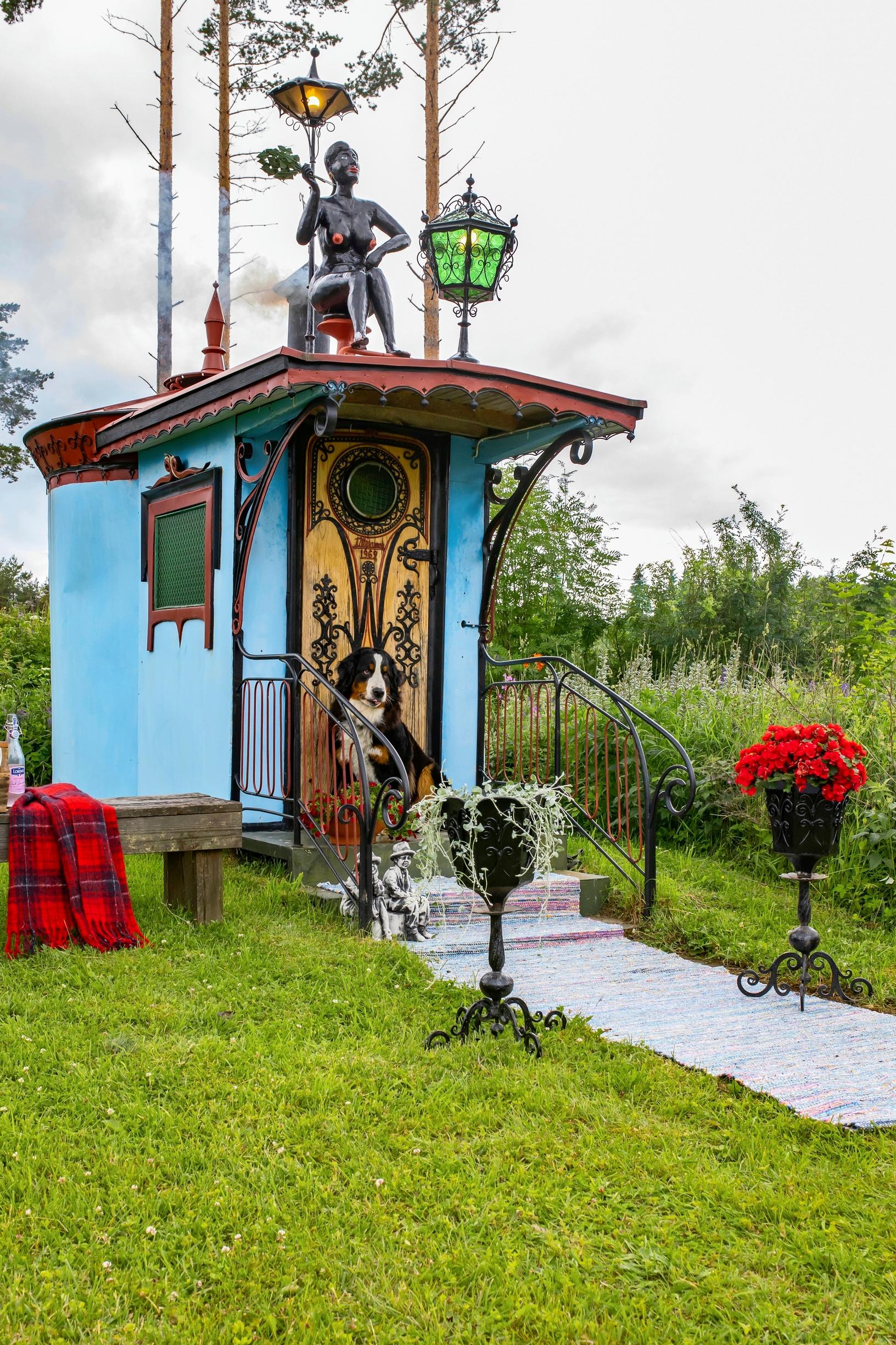 Sininen raudasta tehty sauna, jonka katolla taottu naishahmo
