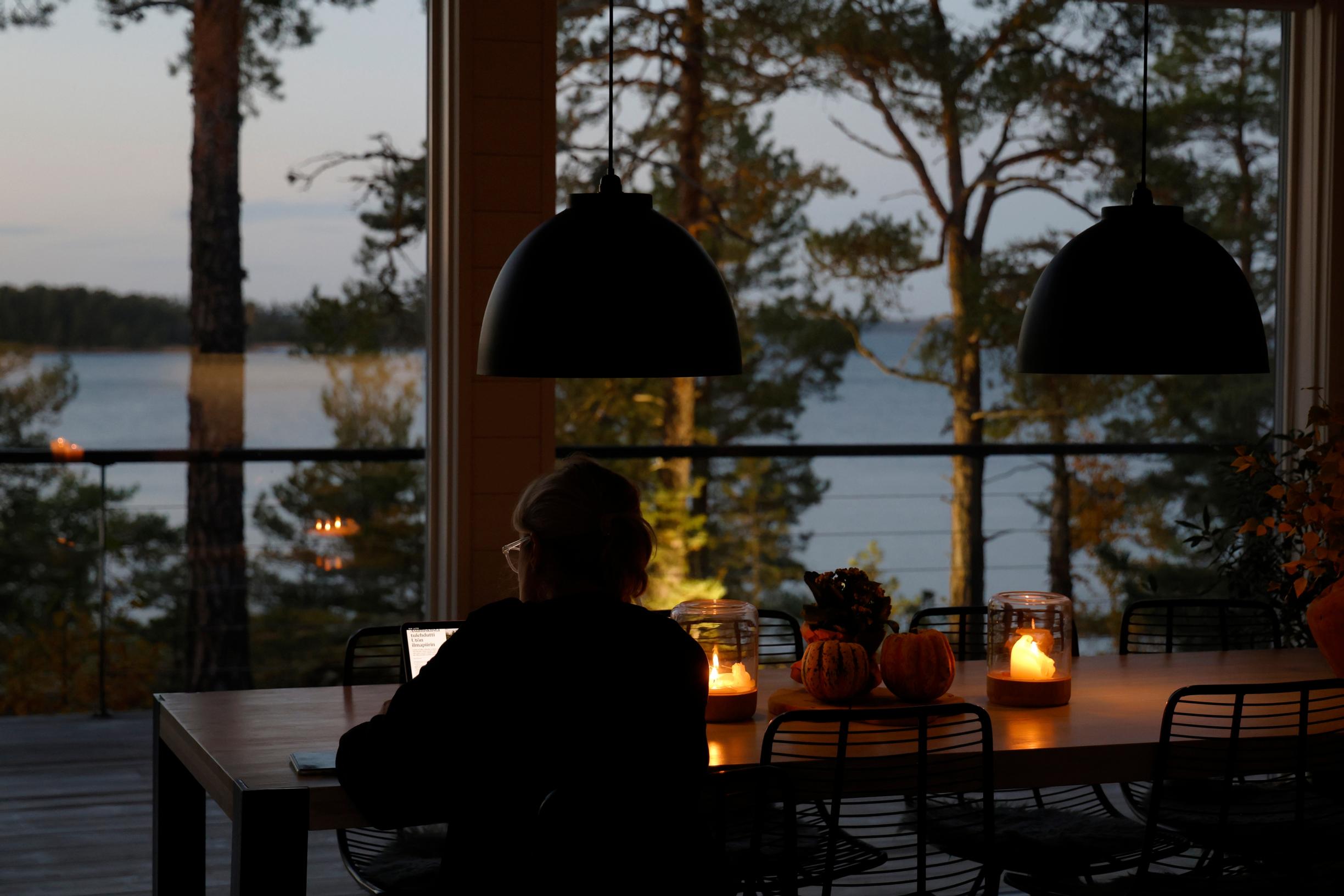 ihminen istuu pöydän ääressä pimeässä illassa, lyhtyjä ja näkymä merelle
