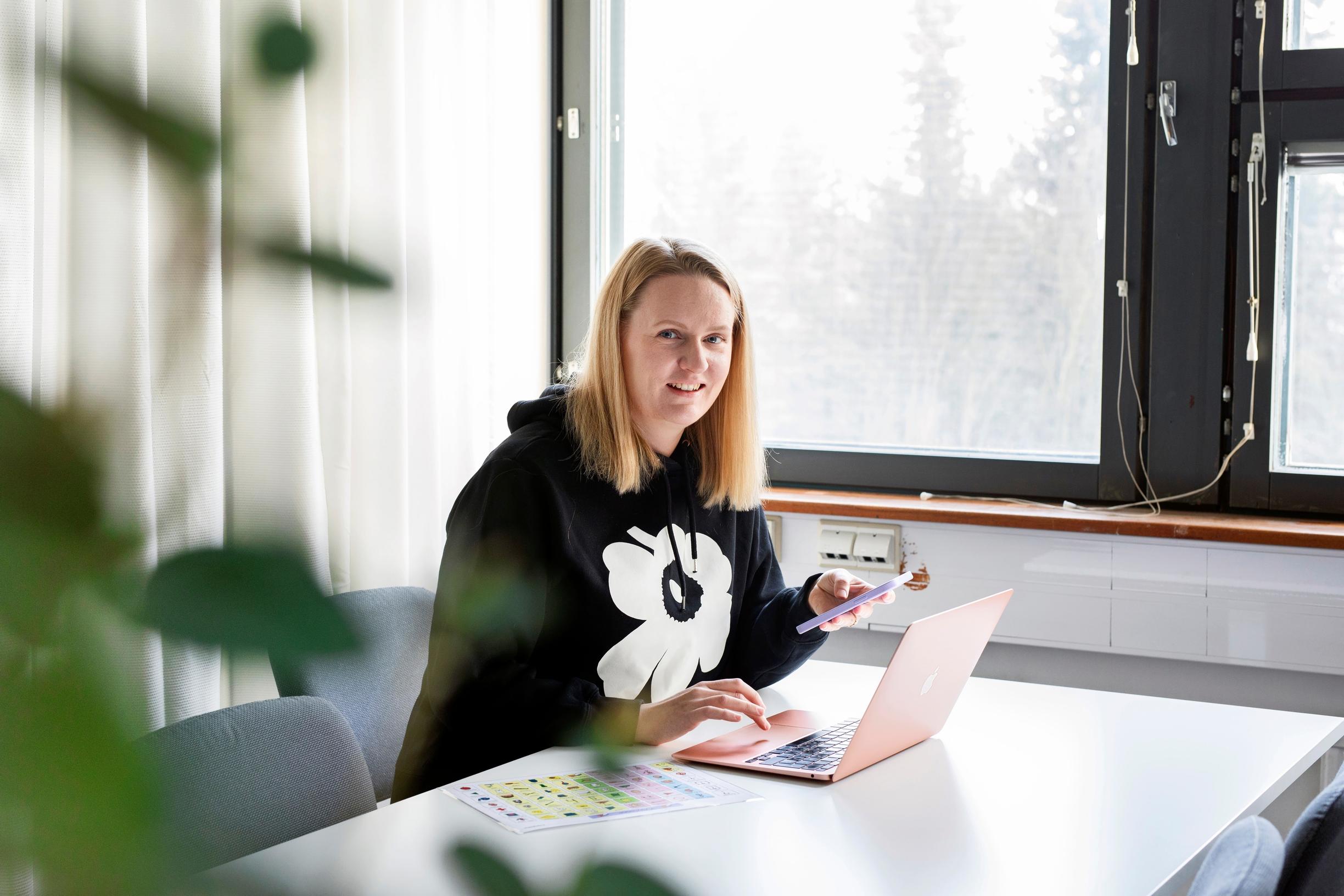nainen istuu ikkunan ääressä tietokoneella