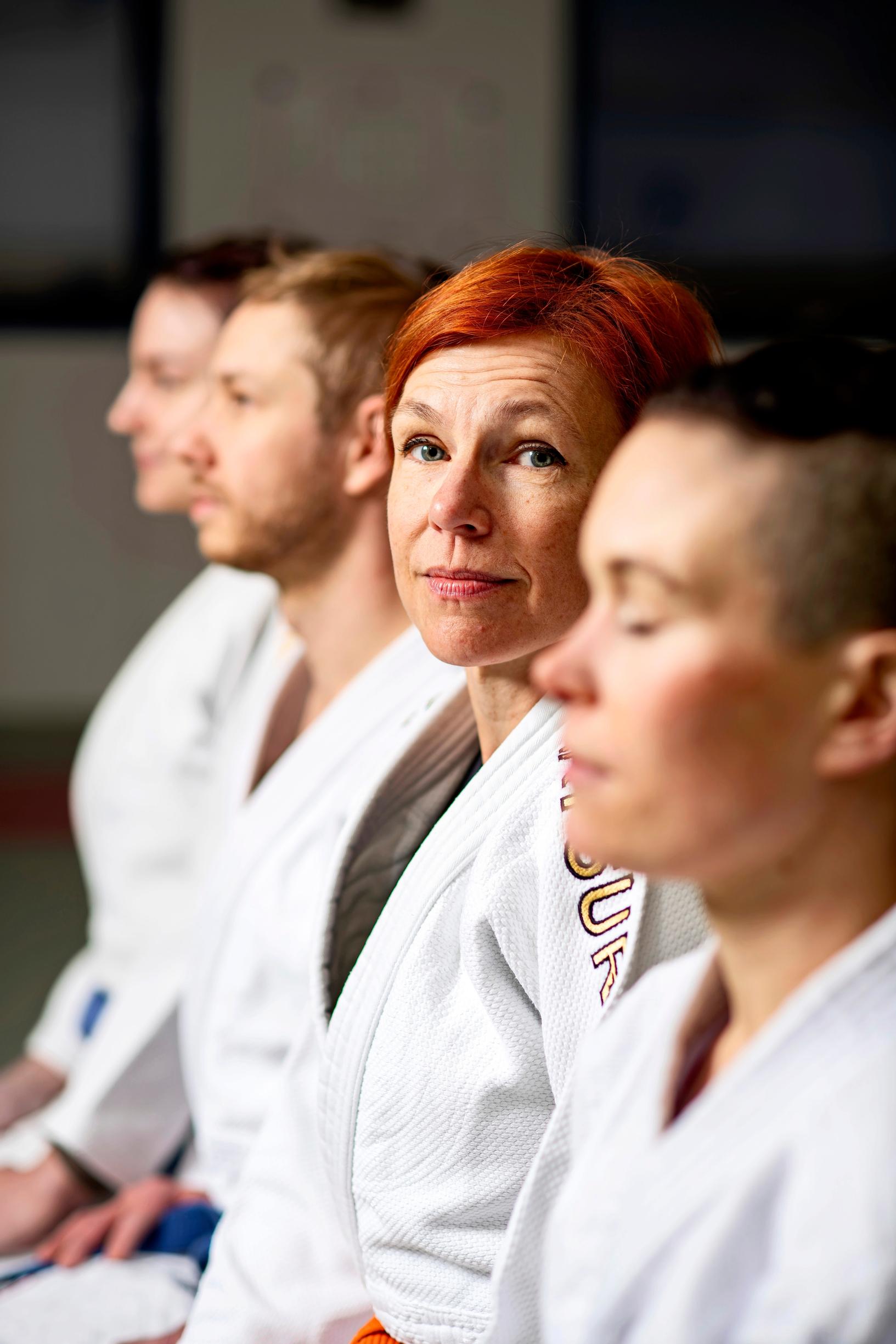 neljä aikuista istuu rivissä judoharjoituksissa