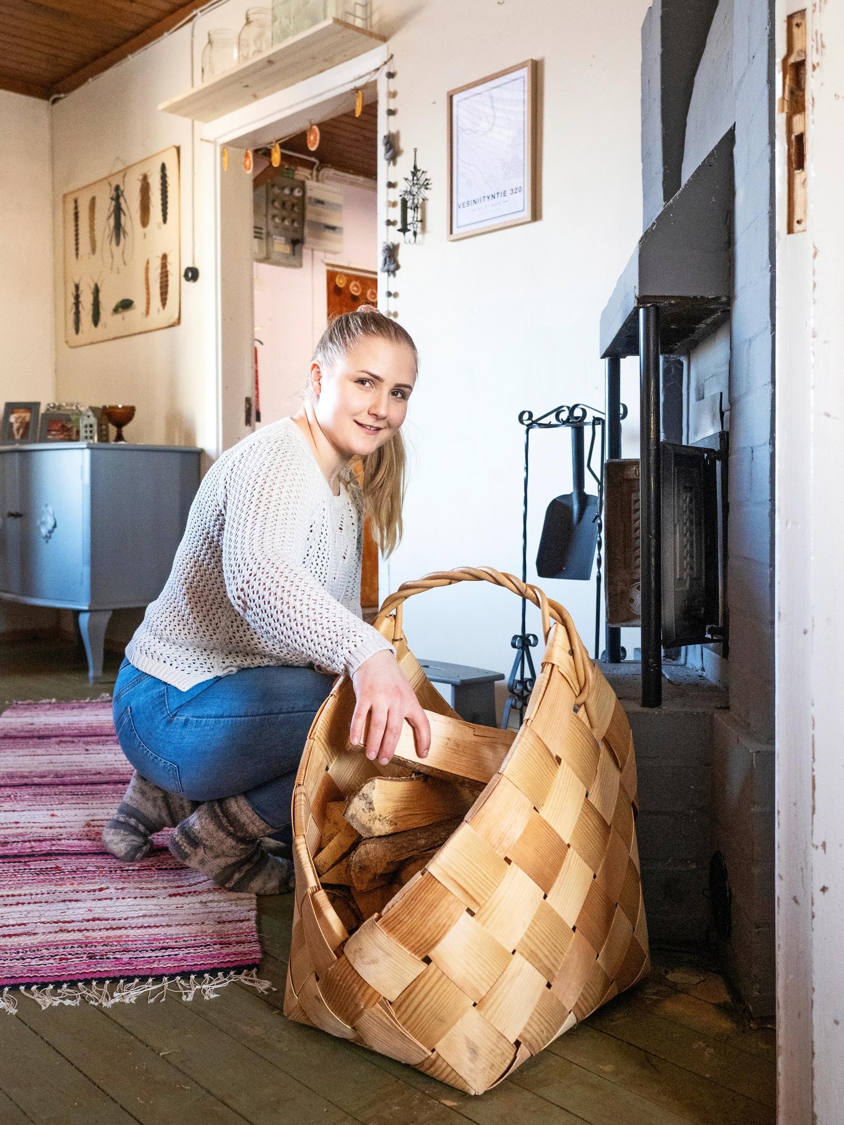 nainen laittaa polttopuita takkaan