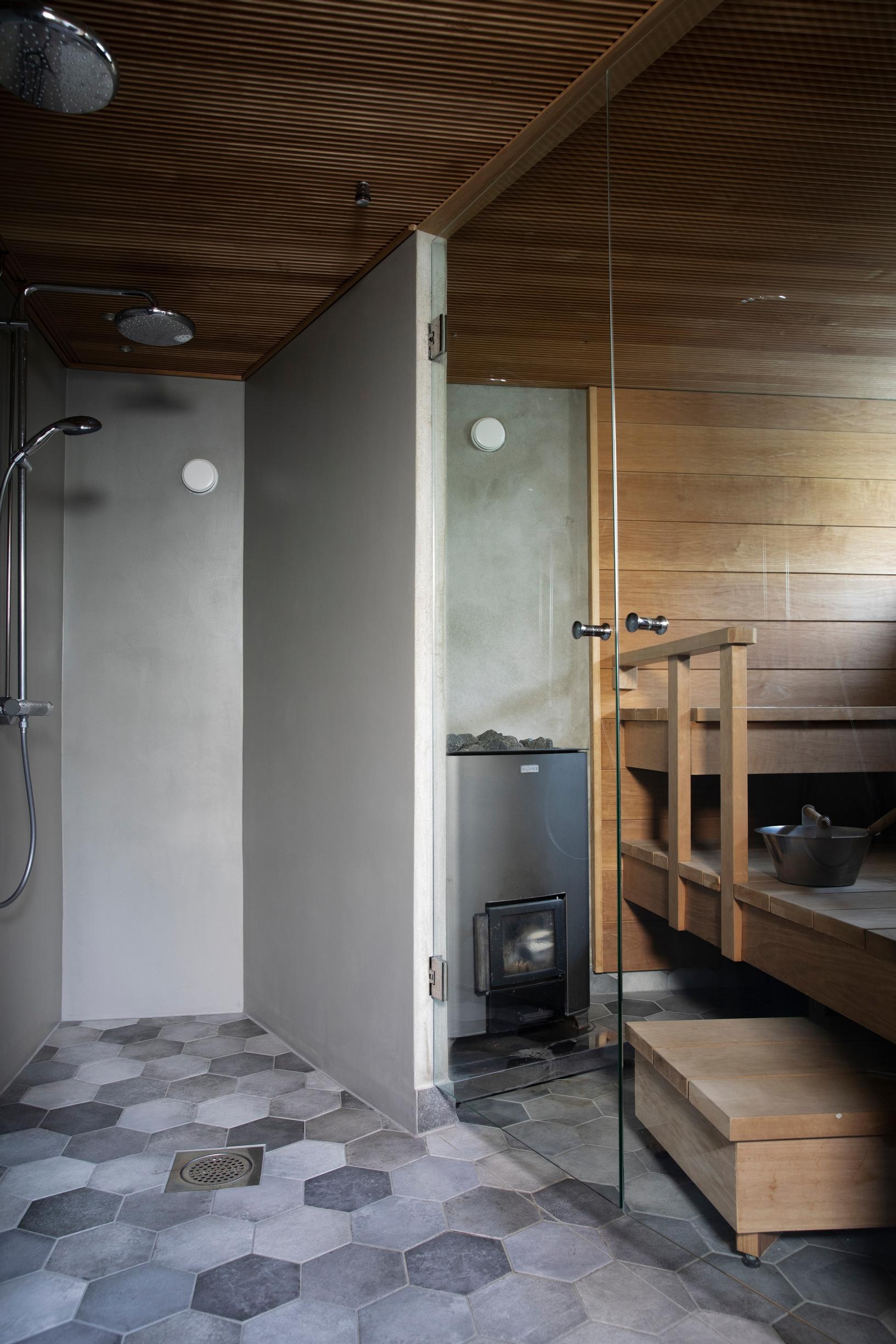 Saunassa on kuusikulmaiset lattialaatat ja suuret lasiovet