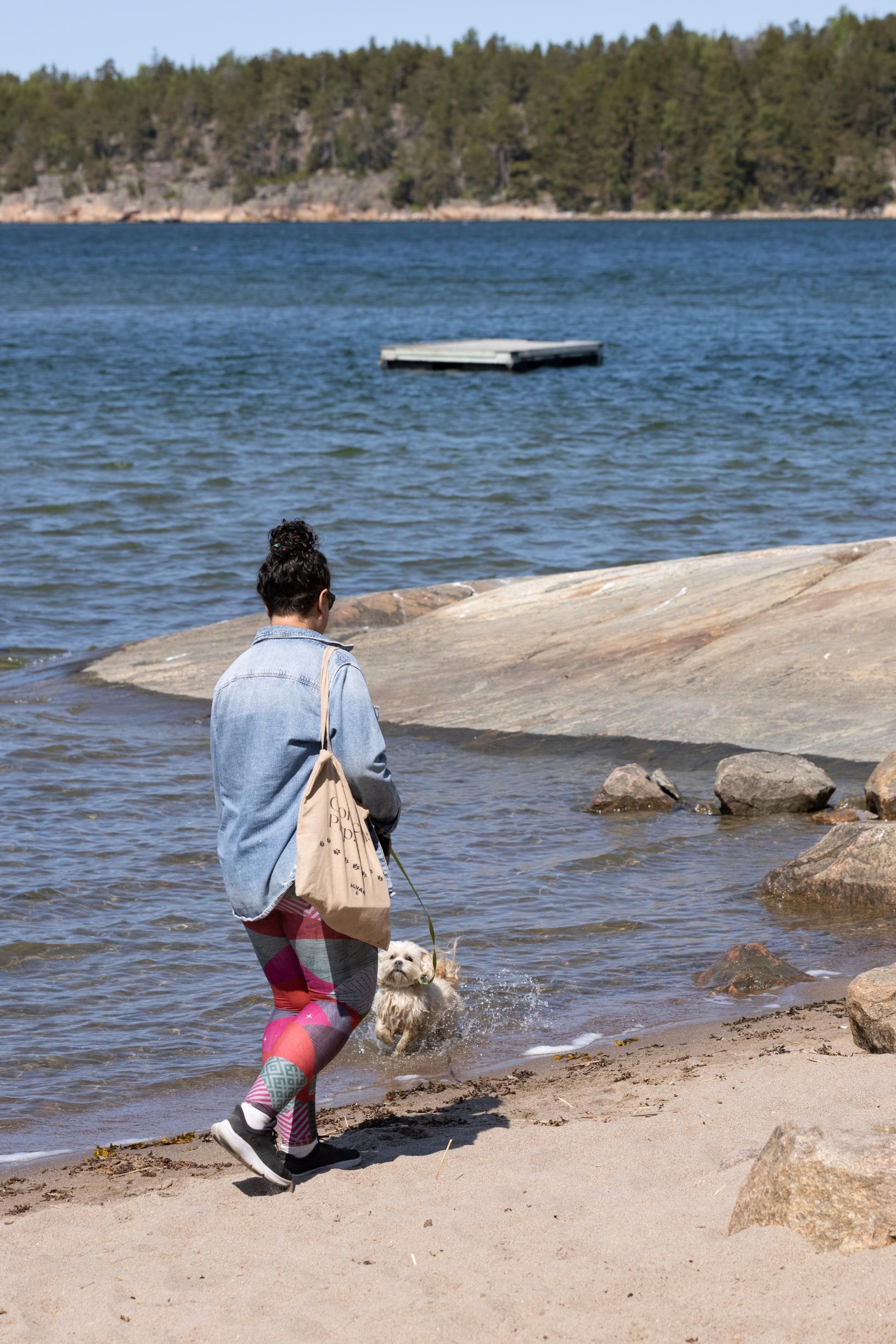 nainen kävelee kassien kanssa meren rannassa hiekalla, kalliota