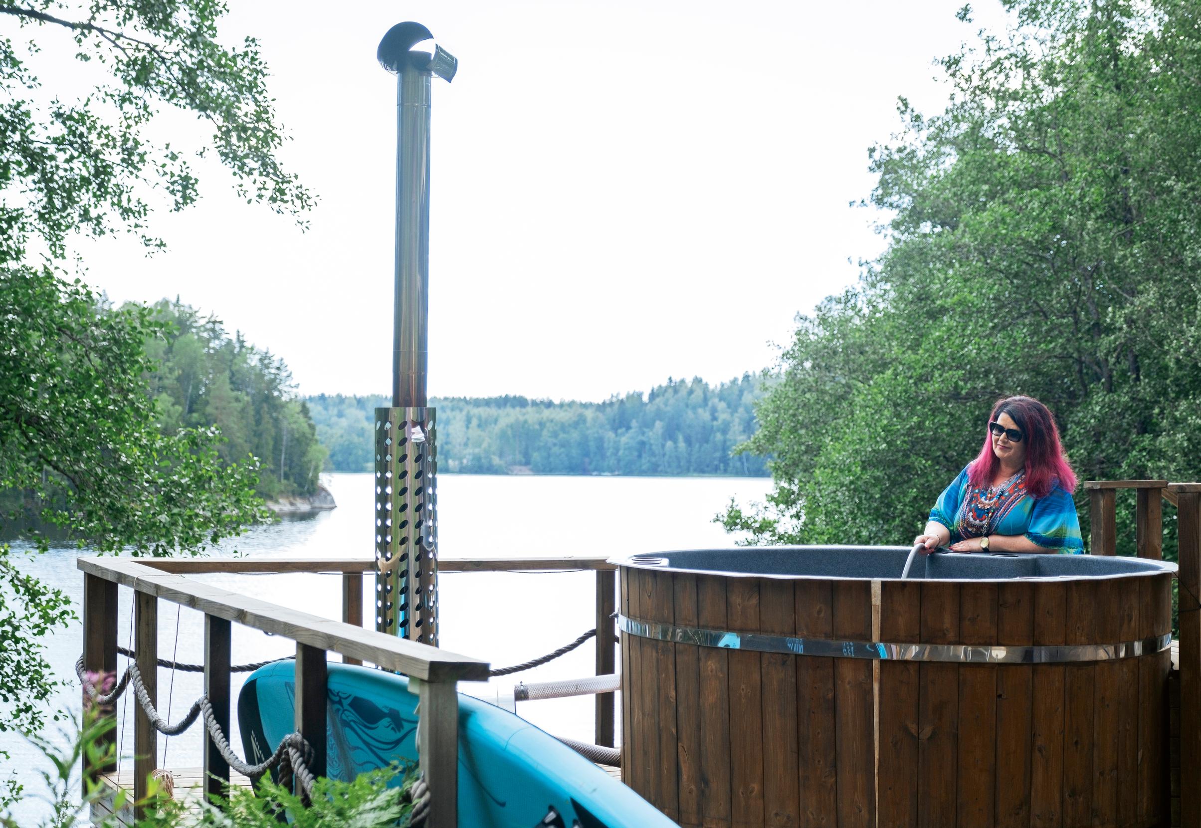 laulaja meiju suvas seisoo paljun vieressä, taustalla järvinäkymä ja metsää