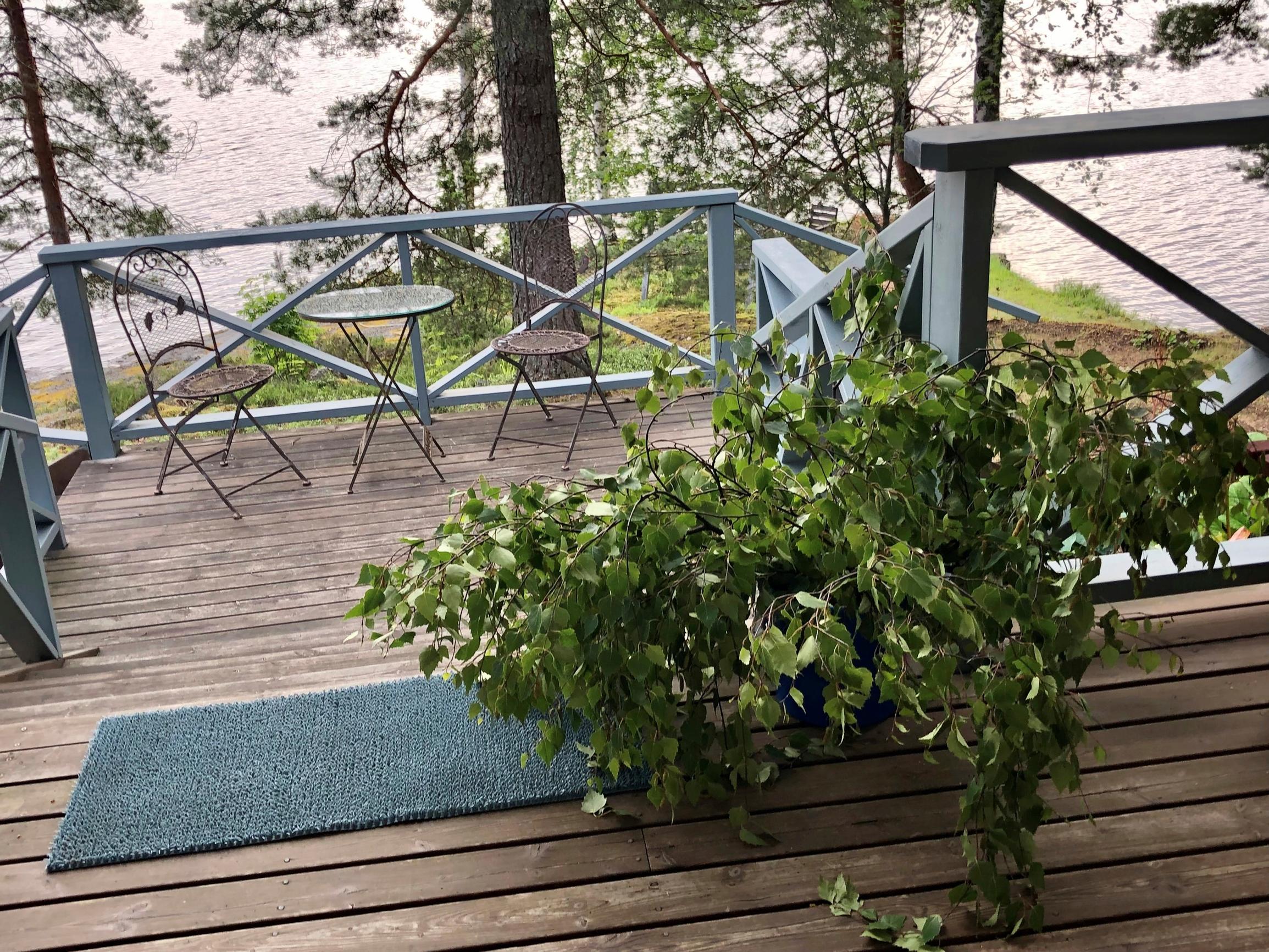 vastoja ja pöytäryhmä Arja Korisevan mökin terassilla, taustalla järvi