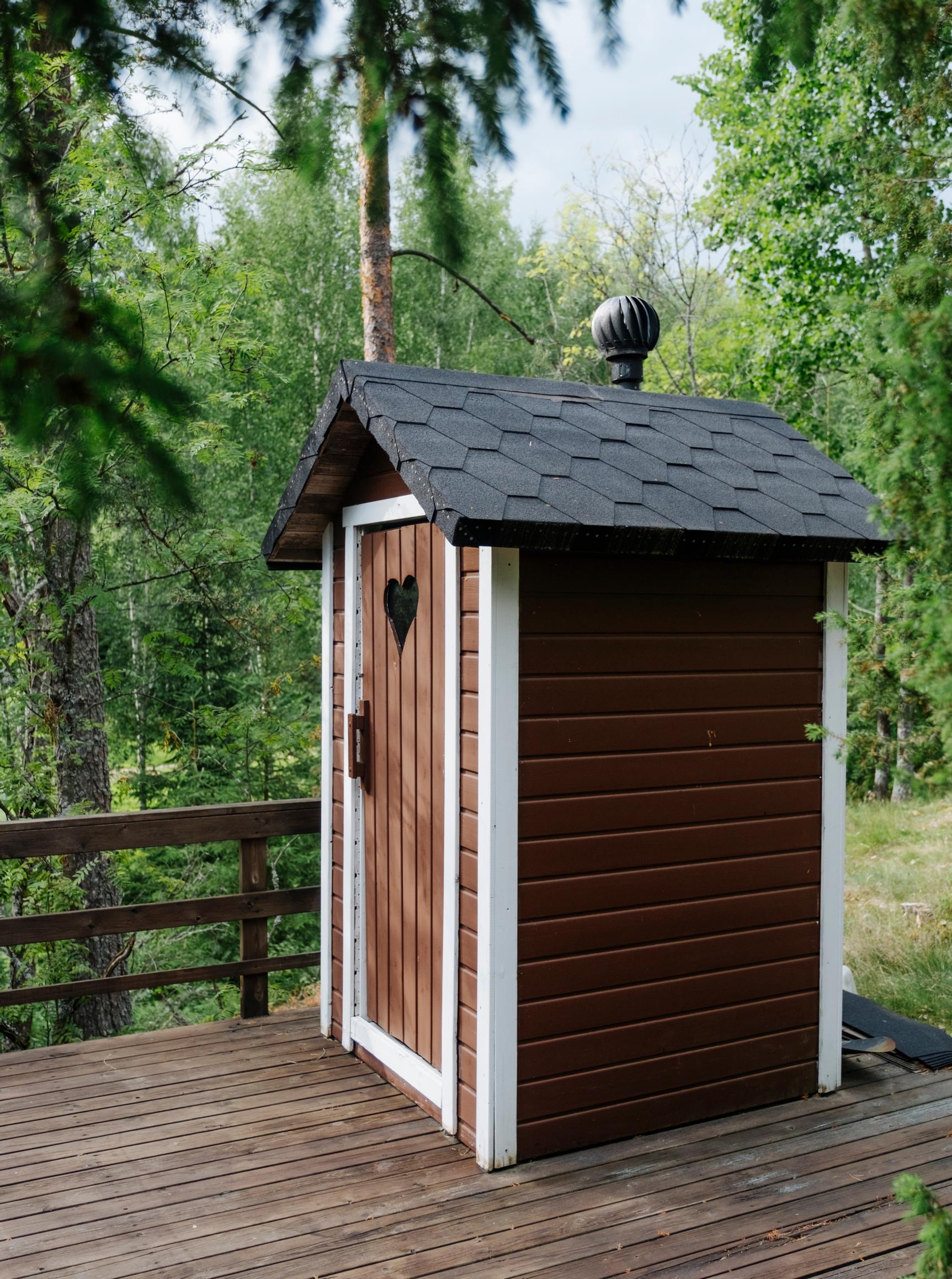 ulkohuussi puuterassilla, kaide ja metsää