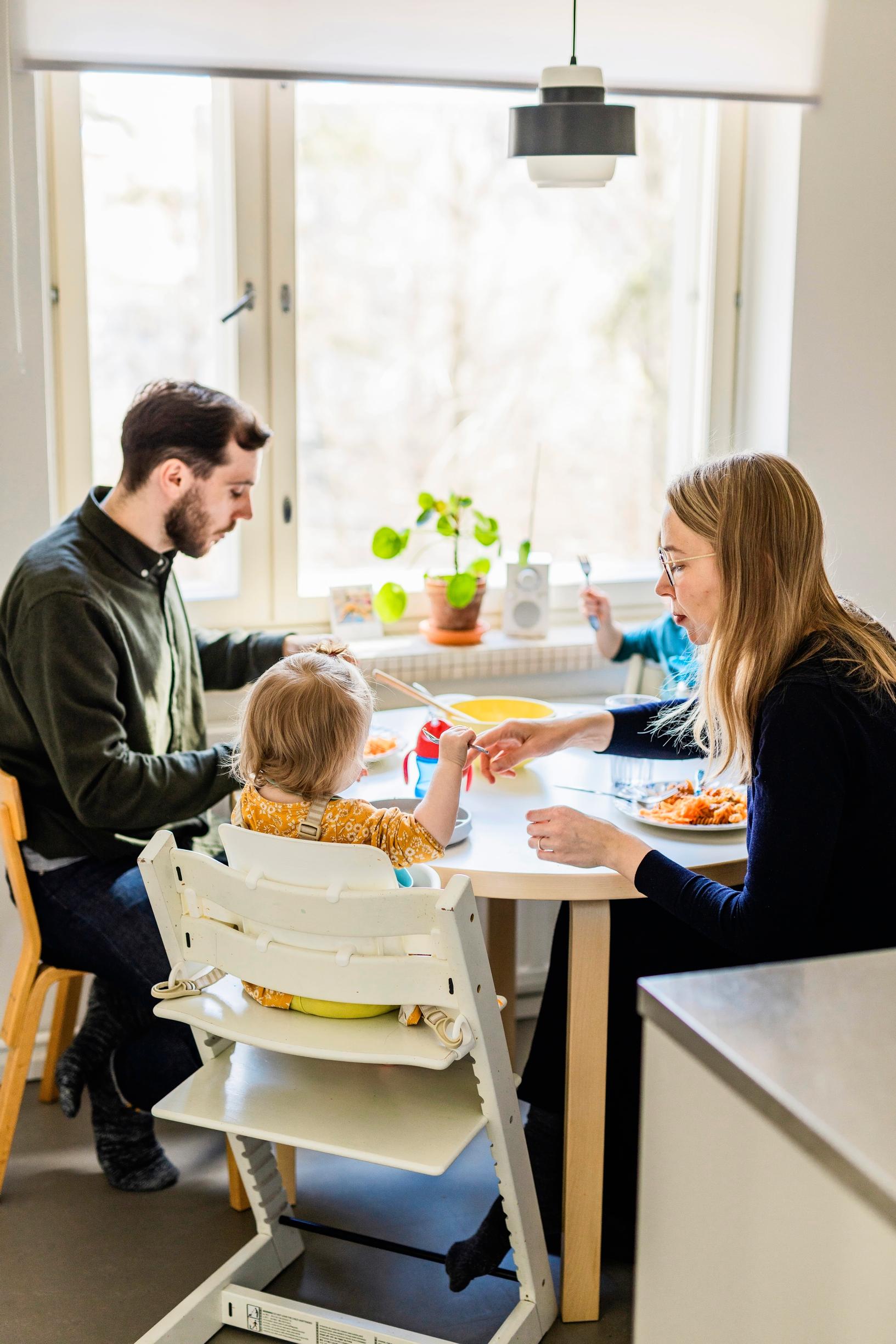 Perhe syö yhdessä ruokapöydän ääressä
