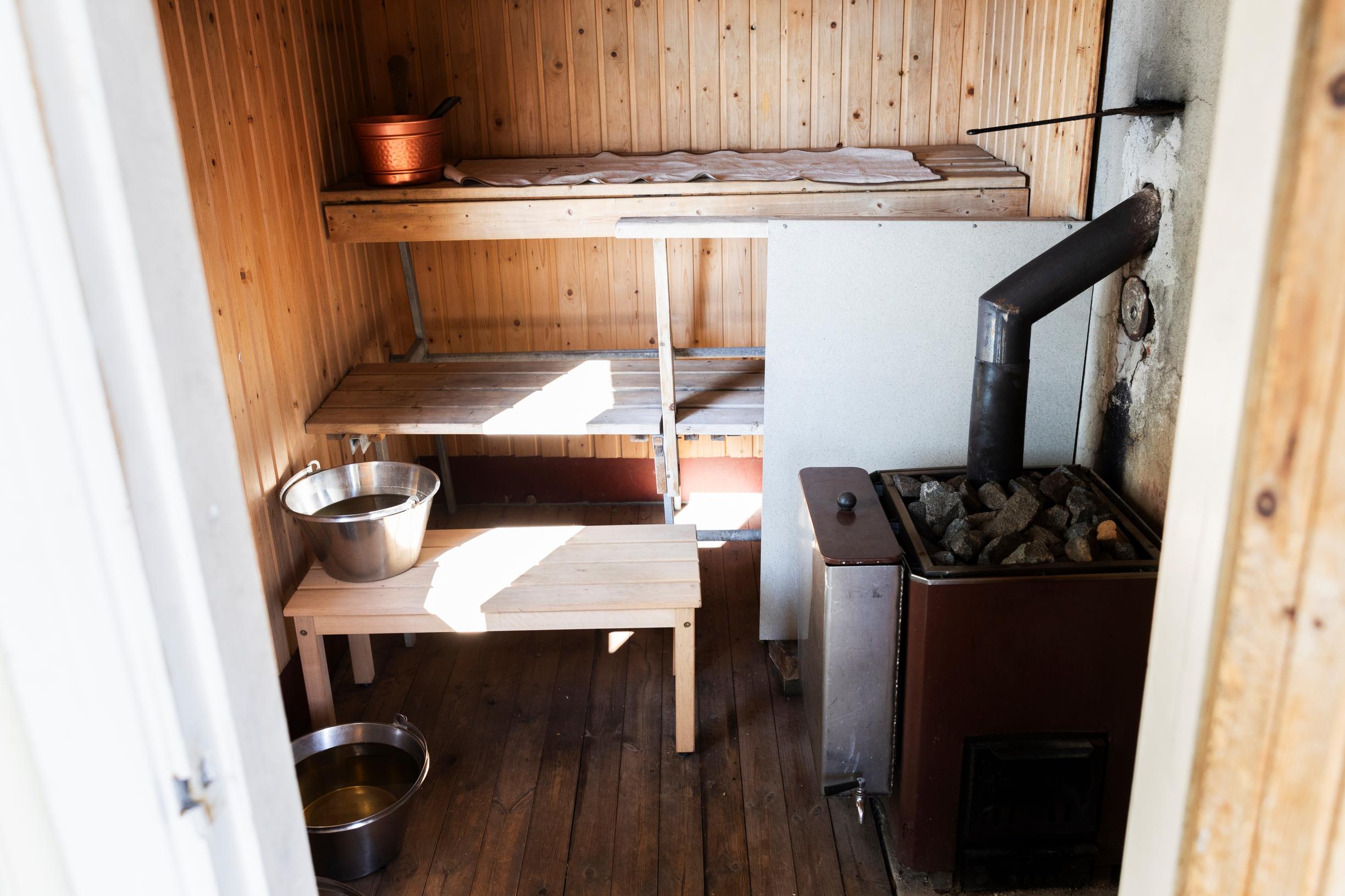 saunan lauteet, kiuas ja ämpäreitä, aurinko paistaa sisään