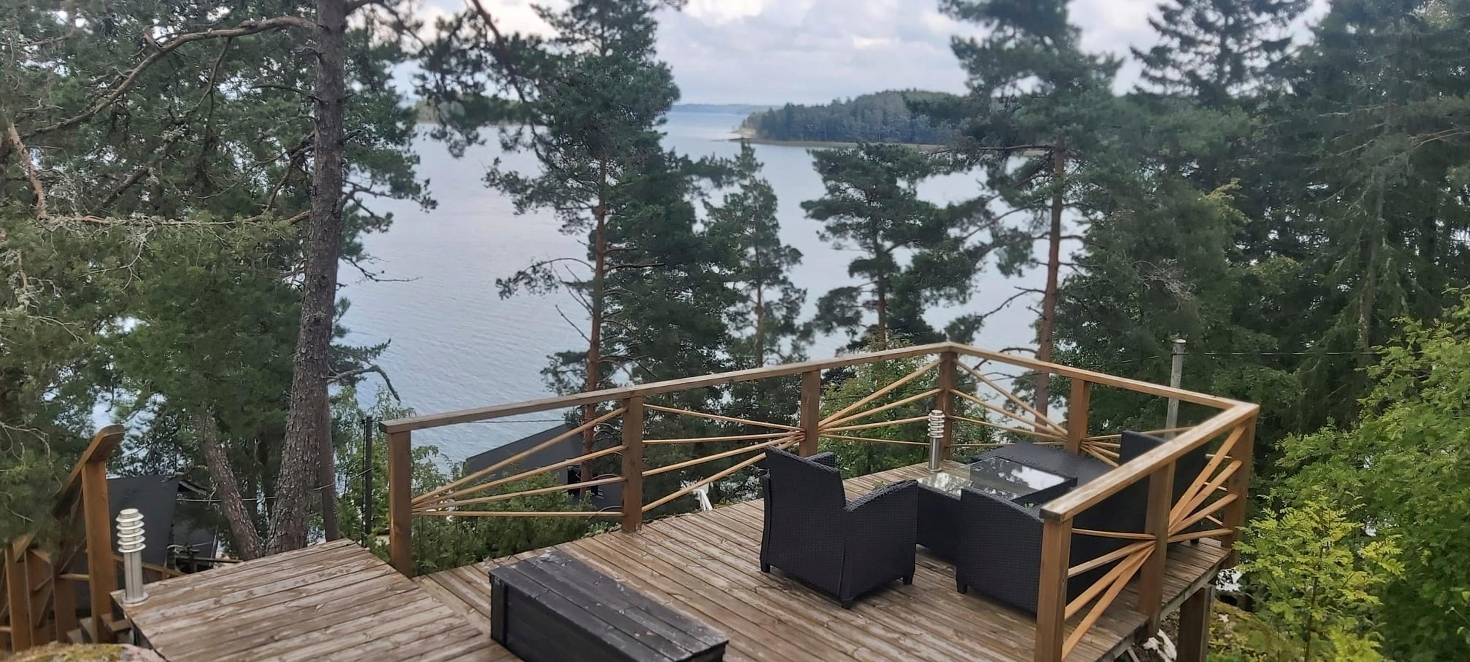 polyrottinkiryhmä terassilla korkealla mäellä, puukaide ja näkymä merelle, mäntyjä