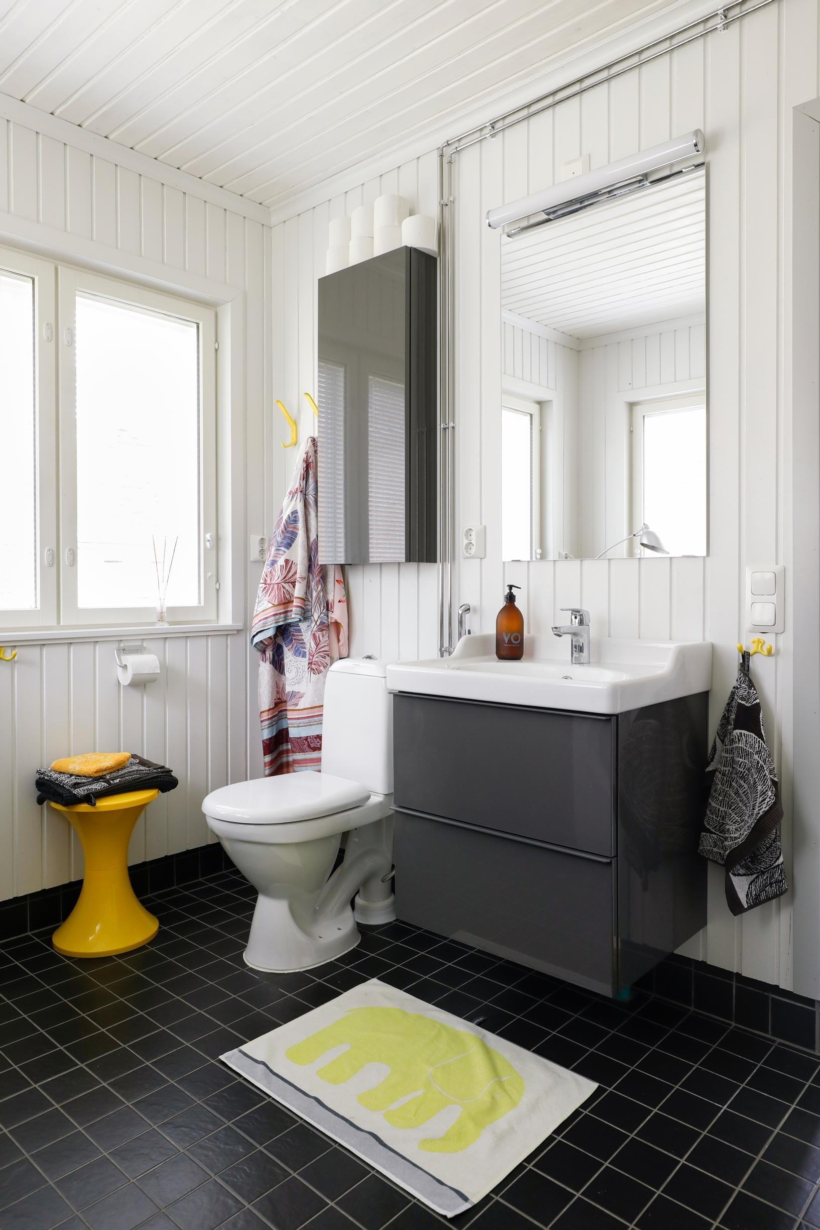 Moderni wc, musta kaakeloitu lattia, valkoinen seinä ja wc-kalusteet.