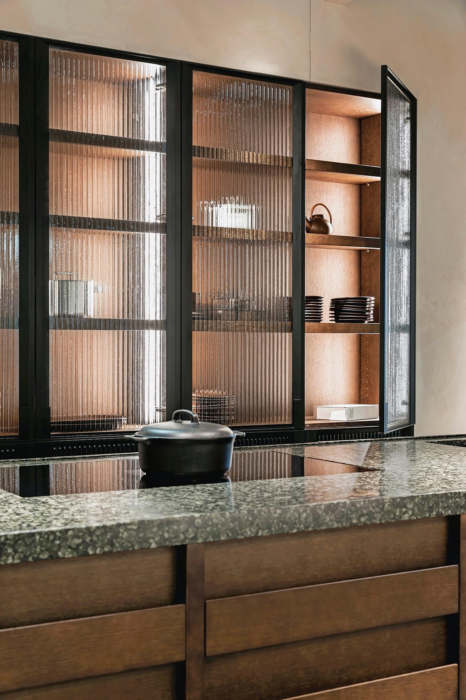 Saari-keittiöiden kaapisto, jossa savunharmaa raitalasi, edessä saareke marmoripinnalla ja induktioliesi