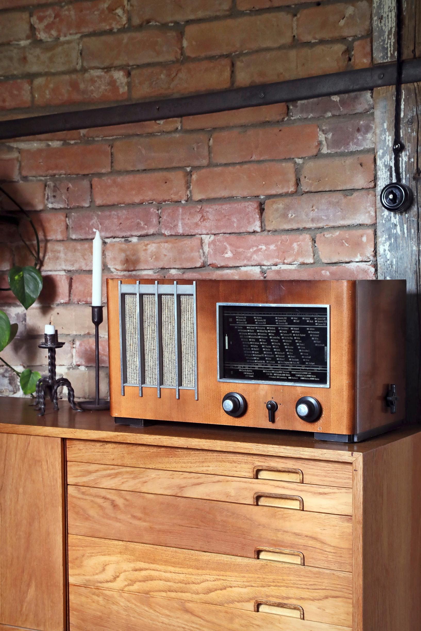 Tiilimuuria vasten on vanha lipasto, jonka päällä on vanha radio.