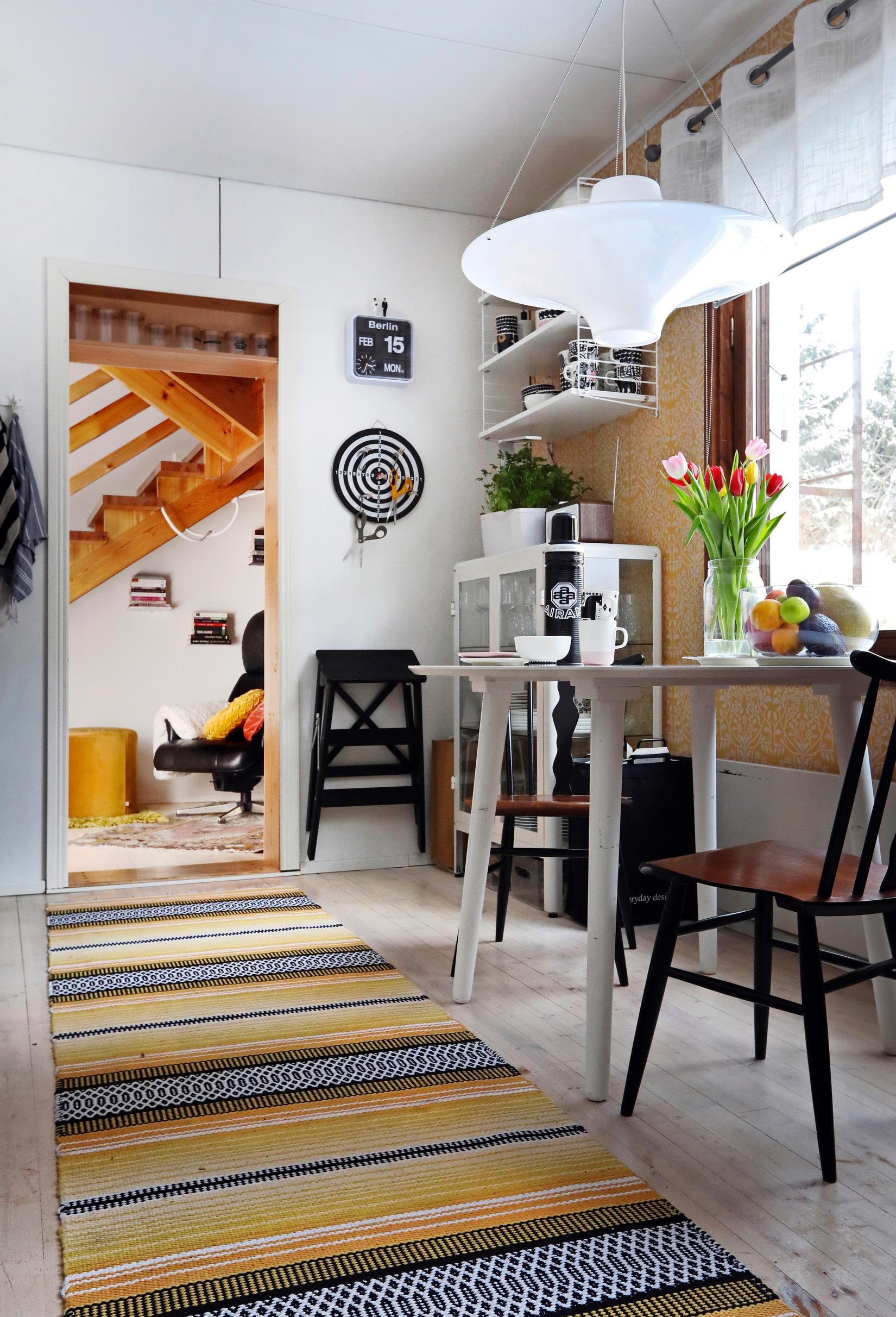 Pitkä kellansävyinen räsymatto ruokapöydän vieressä