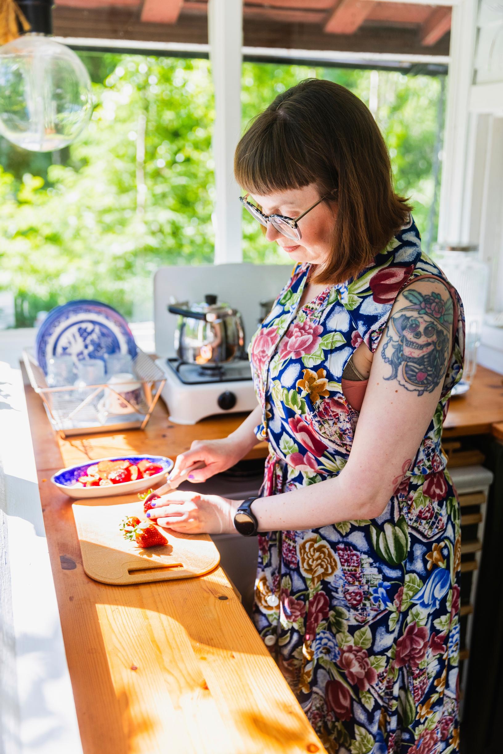 Elina Henttonen pilkkoo mansikoita mökillä