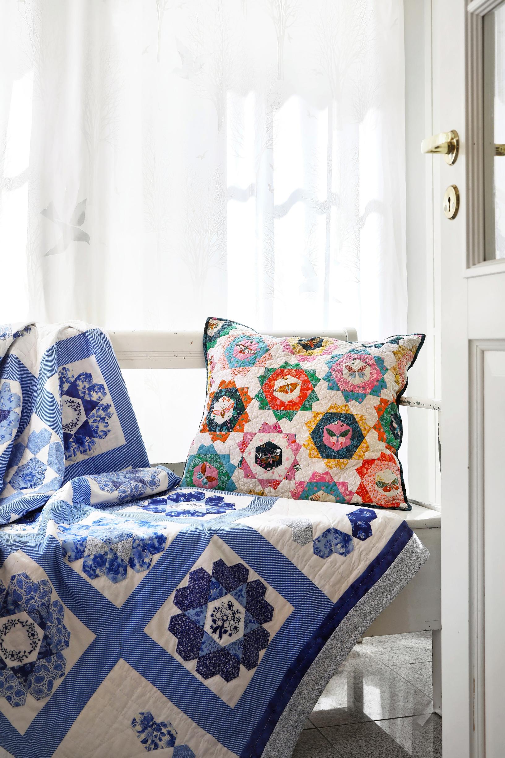 Sinivalkoinen tilkkupeitto ja värikäs tilkkutyyny.