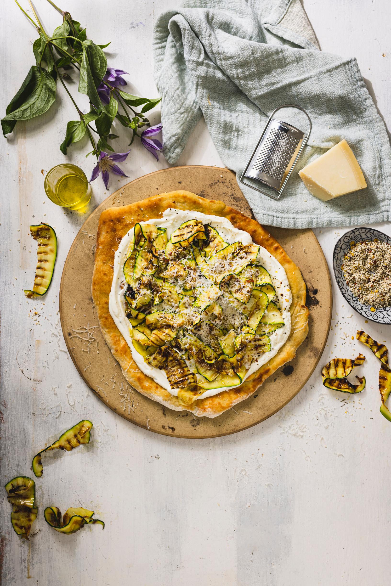 Valkoinen pizza, jonka päällä on grillattua kesäkurpitsaa