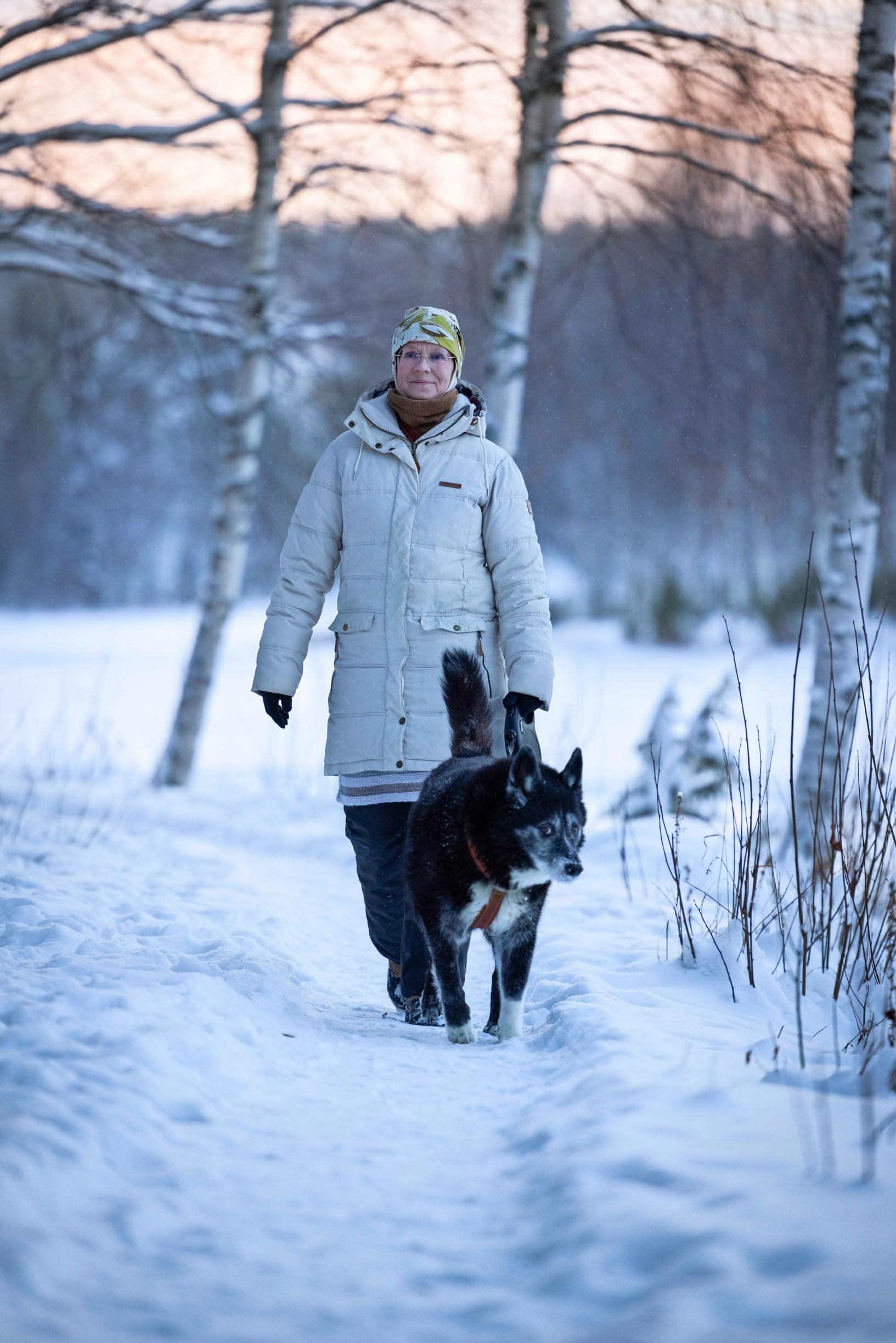 nainen ja koira lenkillä talvisessa metsässä