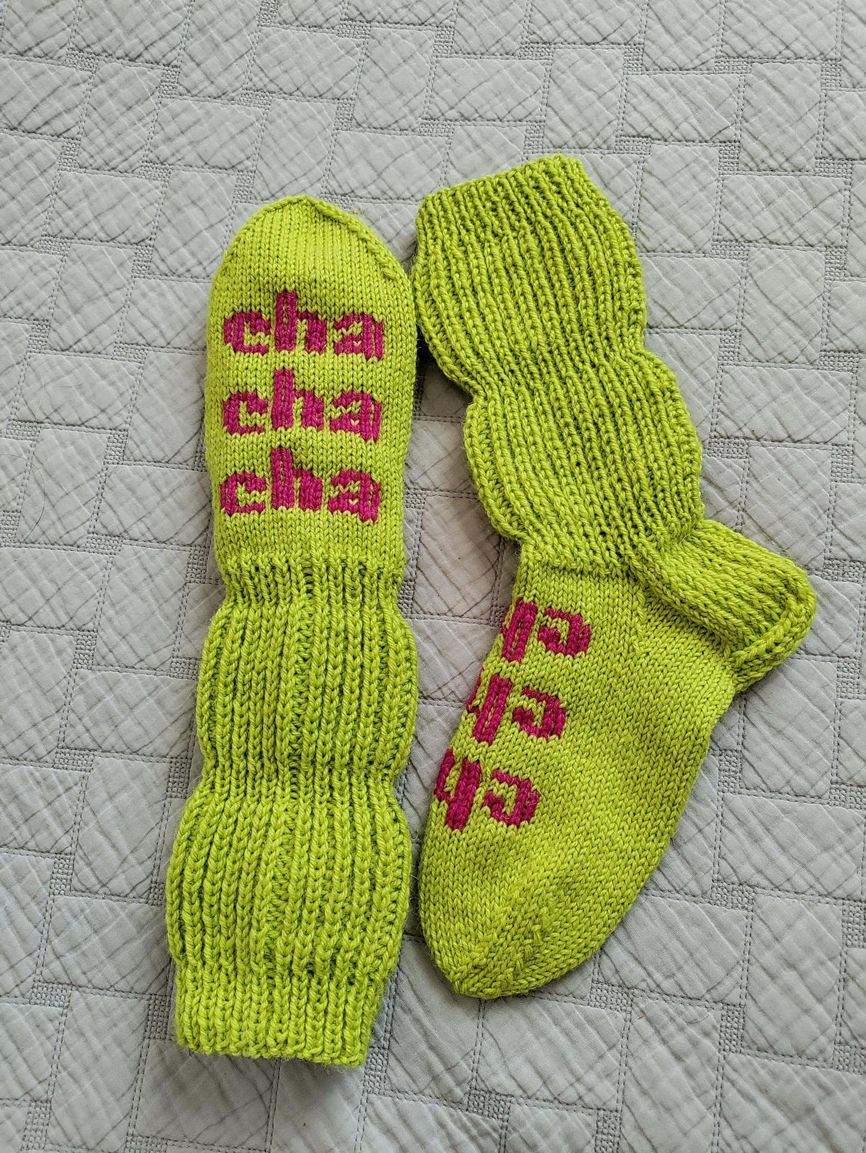 Kirkkaanvihreät ruttusukat, joissa pinkillä teksti ”cha cha cha”.