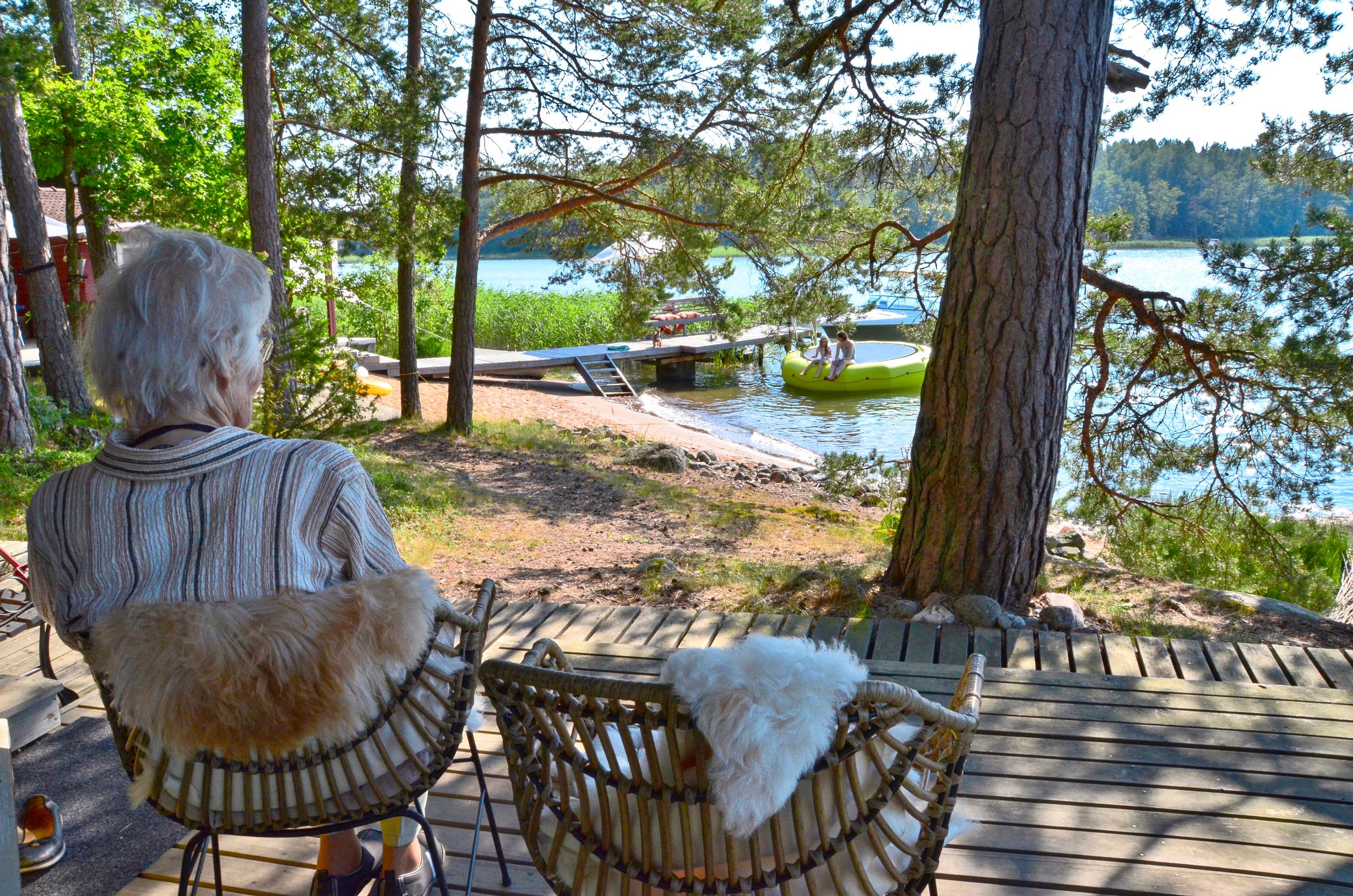 vanha nainen istuu ja katsoo järvelle 